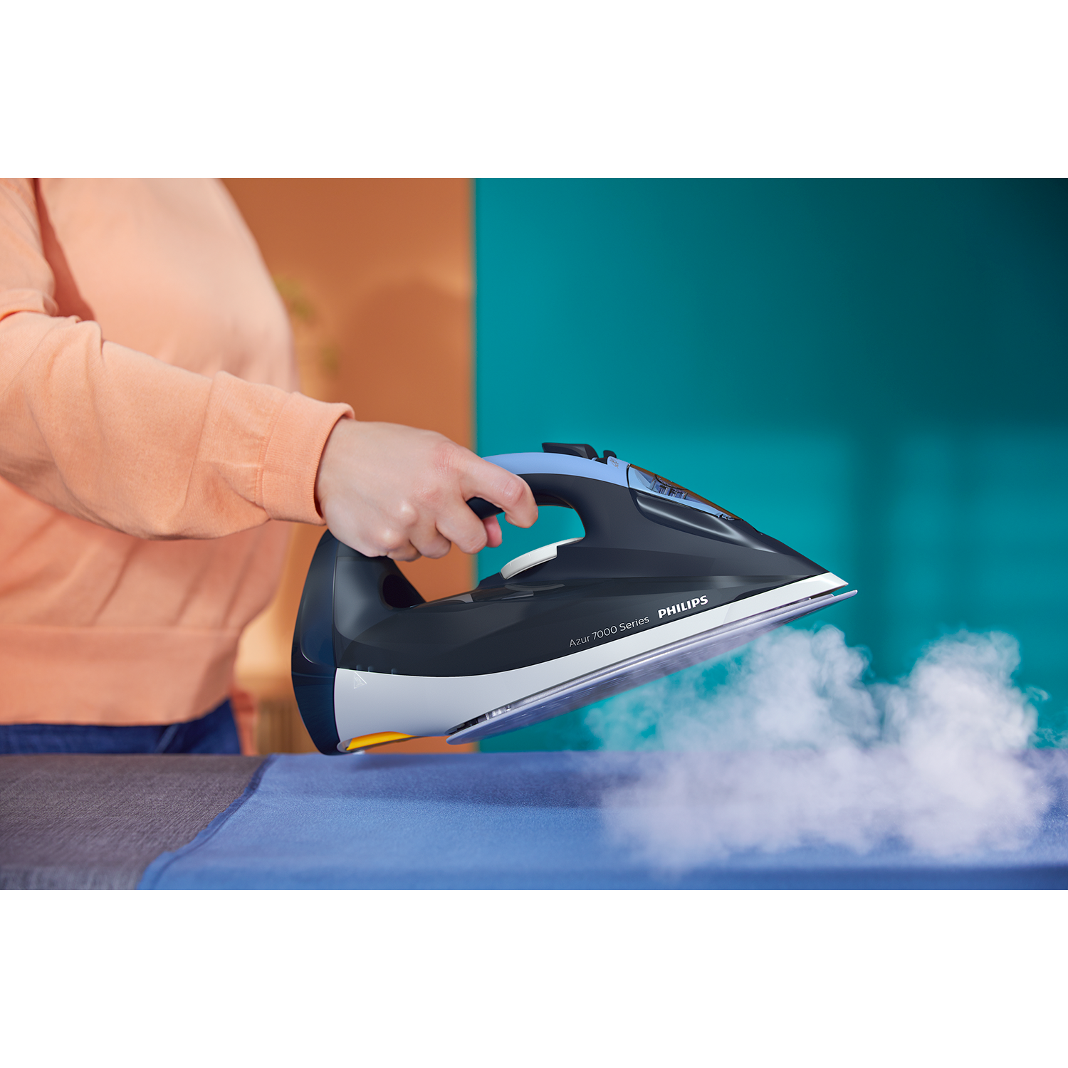 Mujer planchando tela azul con plancha Philips, vapor visible.