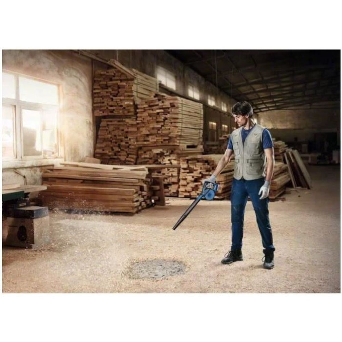Hombre usando un soplador de hojas en un taller con madera.