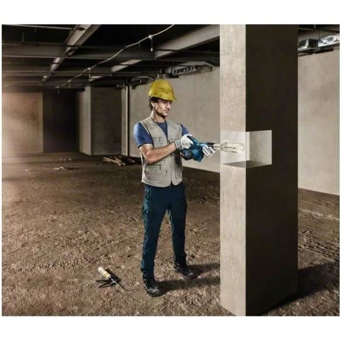 Trabajador usando taladro para cortar pared de concreto, sitio de construcción.