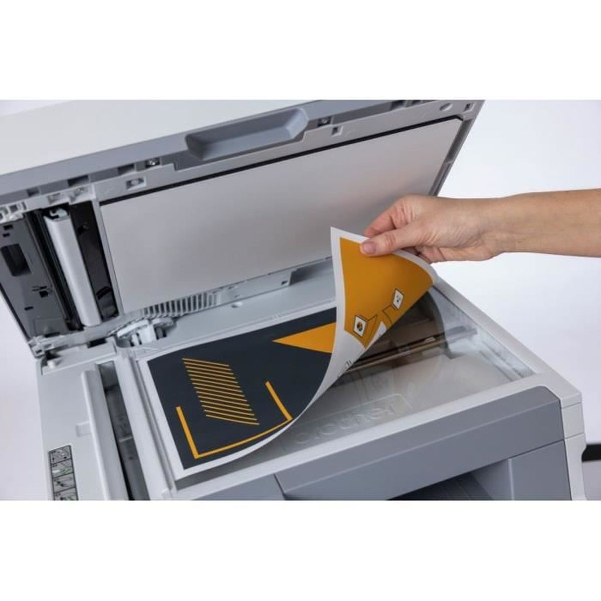 Ręka osoby podnosi kartkę papieru z białej drukarki.