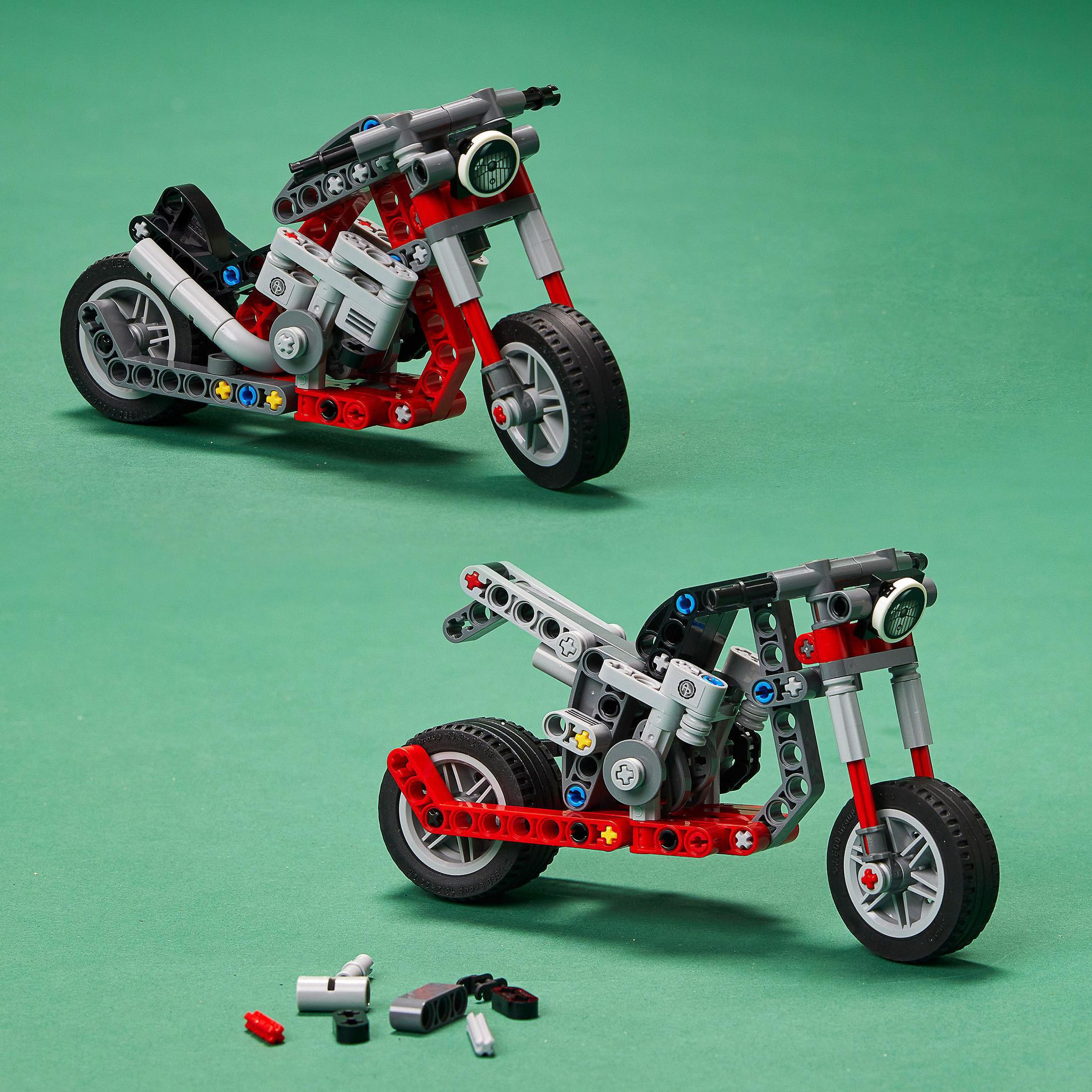 Yeşil bir yüzey üzerinde iki Lego motosiklet, kırmızı ve gri. Önünde bazı gevşek parçalar.
