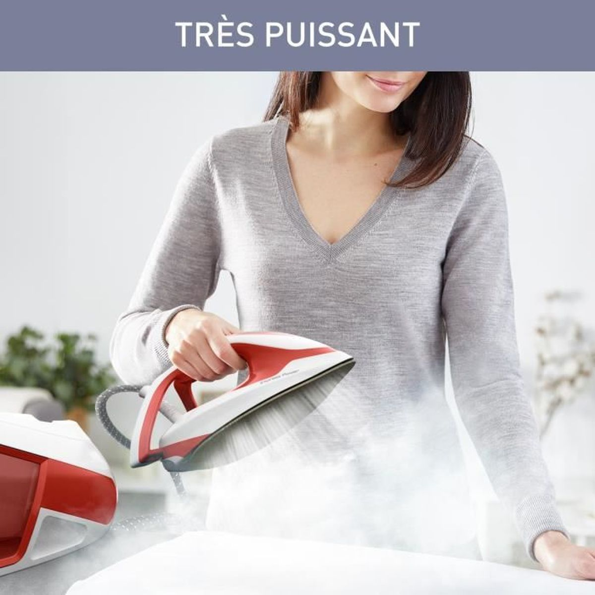 Una donna che stira un tessuto bianco con un ferro da stiro rosso e bianco, il vapore sale.