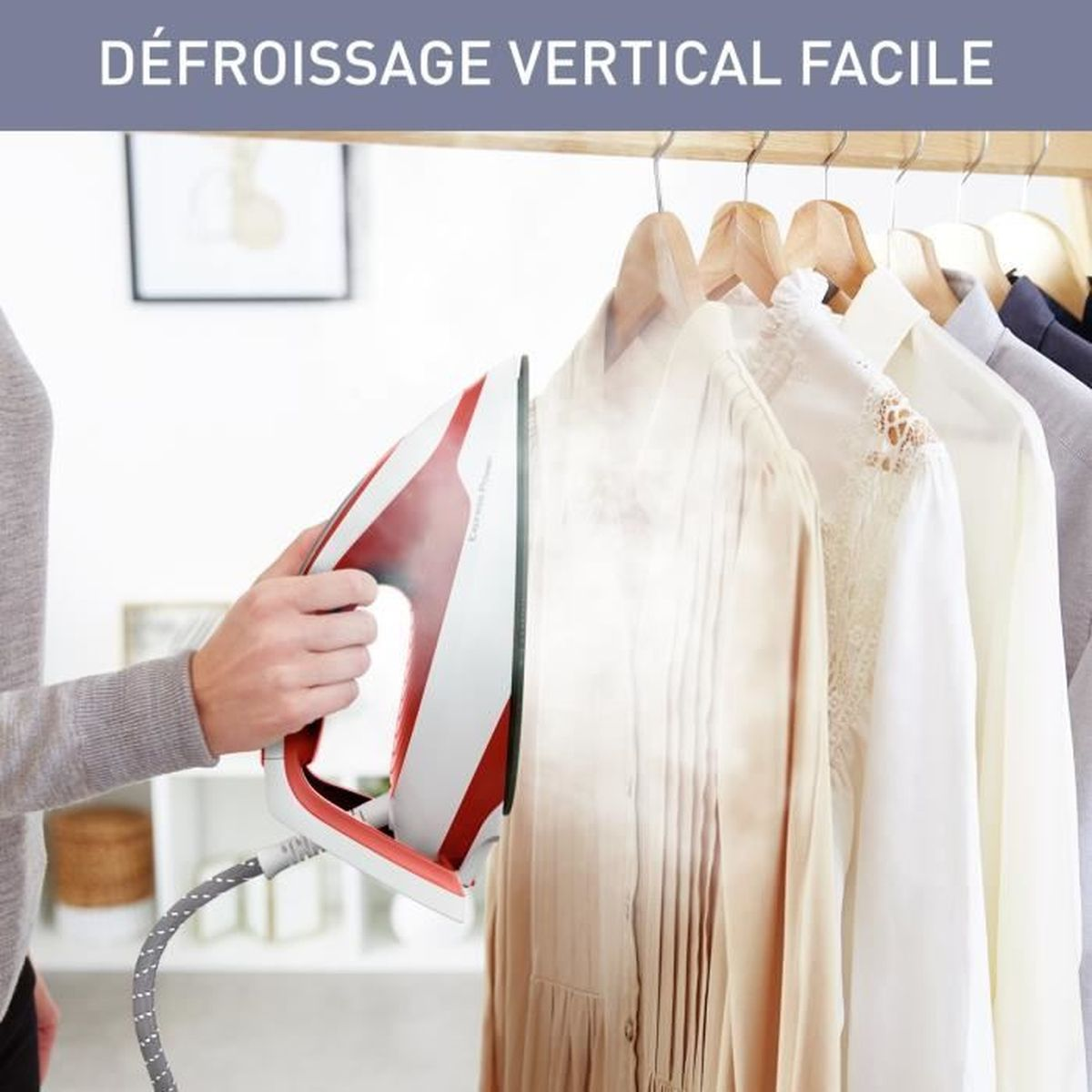 Ferro da stiro a vapore su vestiti appesi, persona che tiene il ferro.