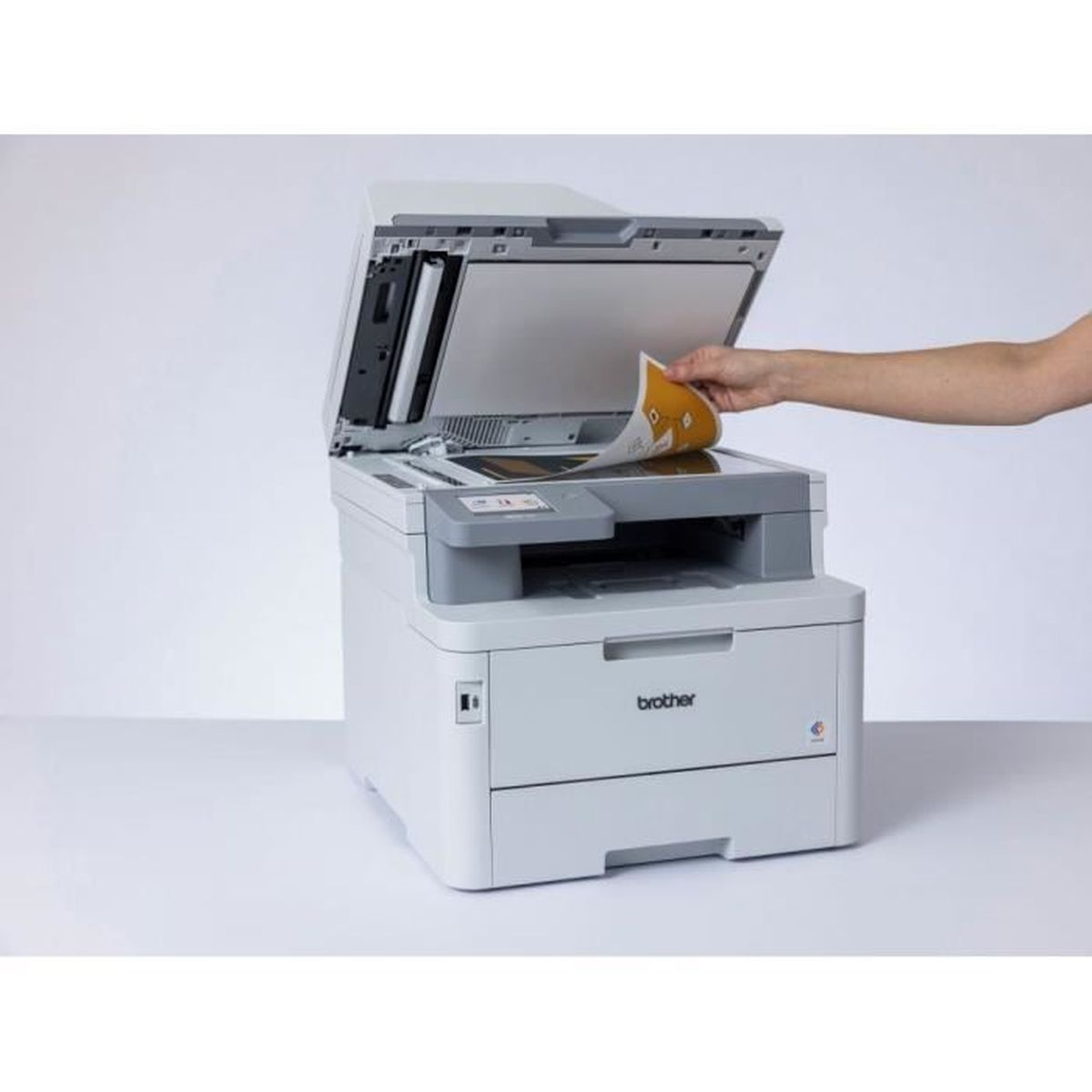 Een witte Brother-printer met een hand die een papier invoegt, lichte achtergrond.