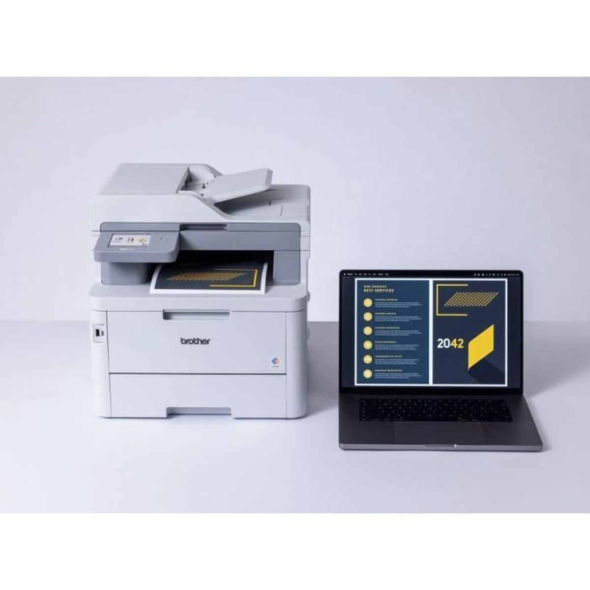 Een printer en een laptop op een wit oppervlak.