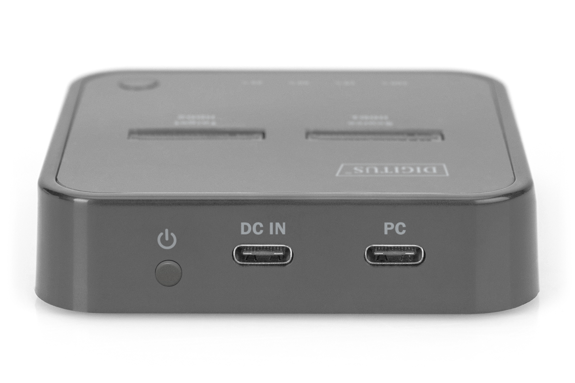 Donkergrijs apparaat met de woorden DC IN en PC. Het heeft een aan/uit-knop.
