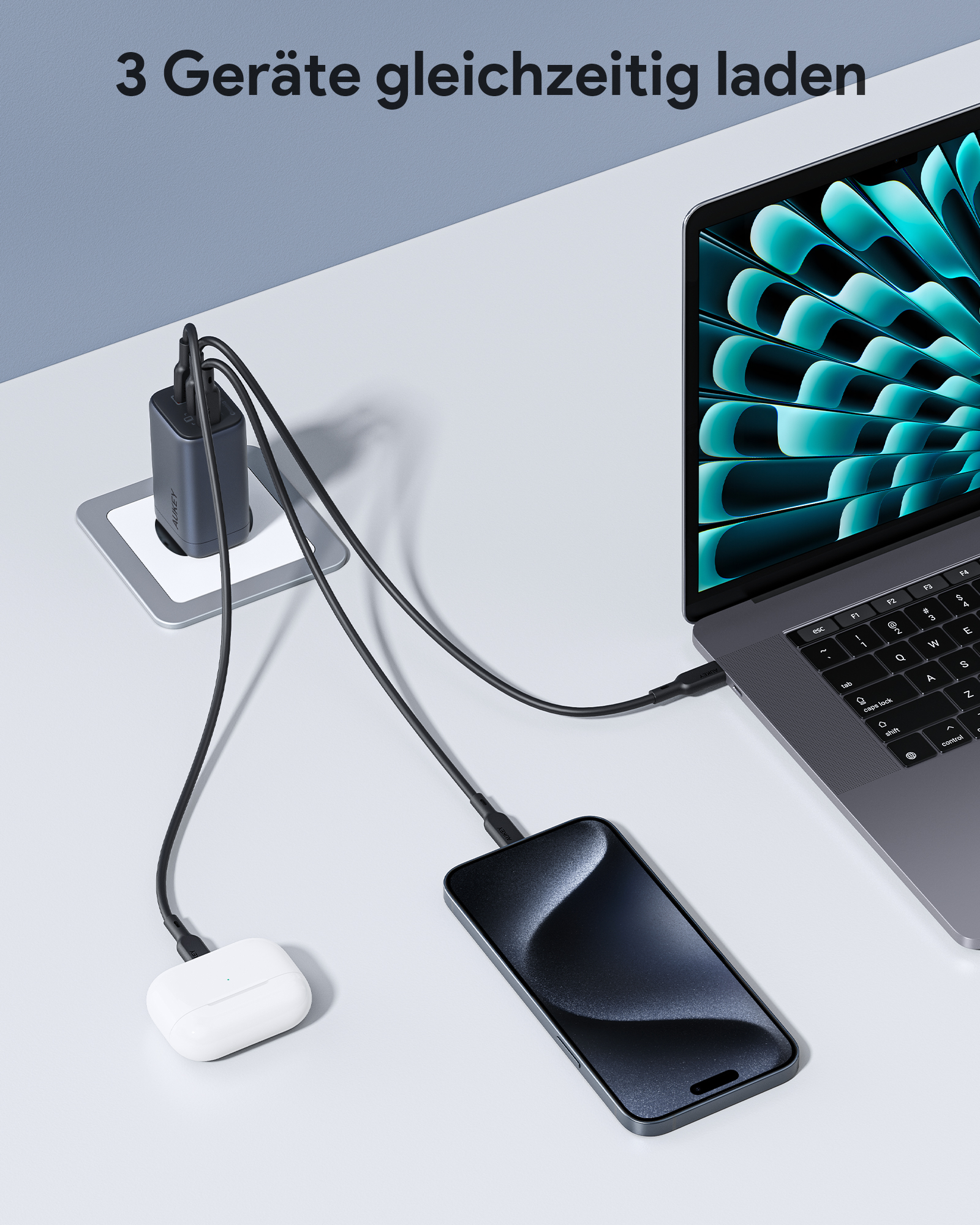 Ein Ladegerät ist mit einem Laptop, einem Telefon und Ohrhörern verbunden. Alle sind auf einer weißen Oberfläche.