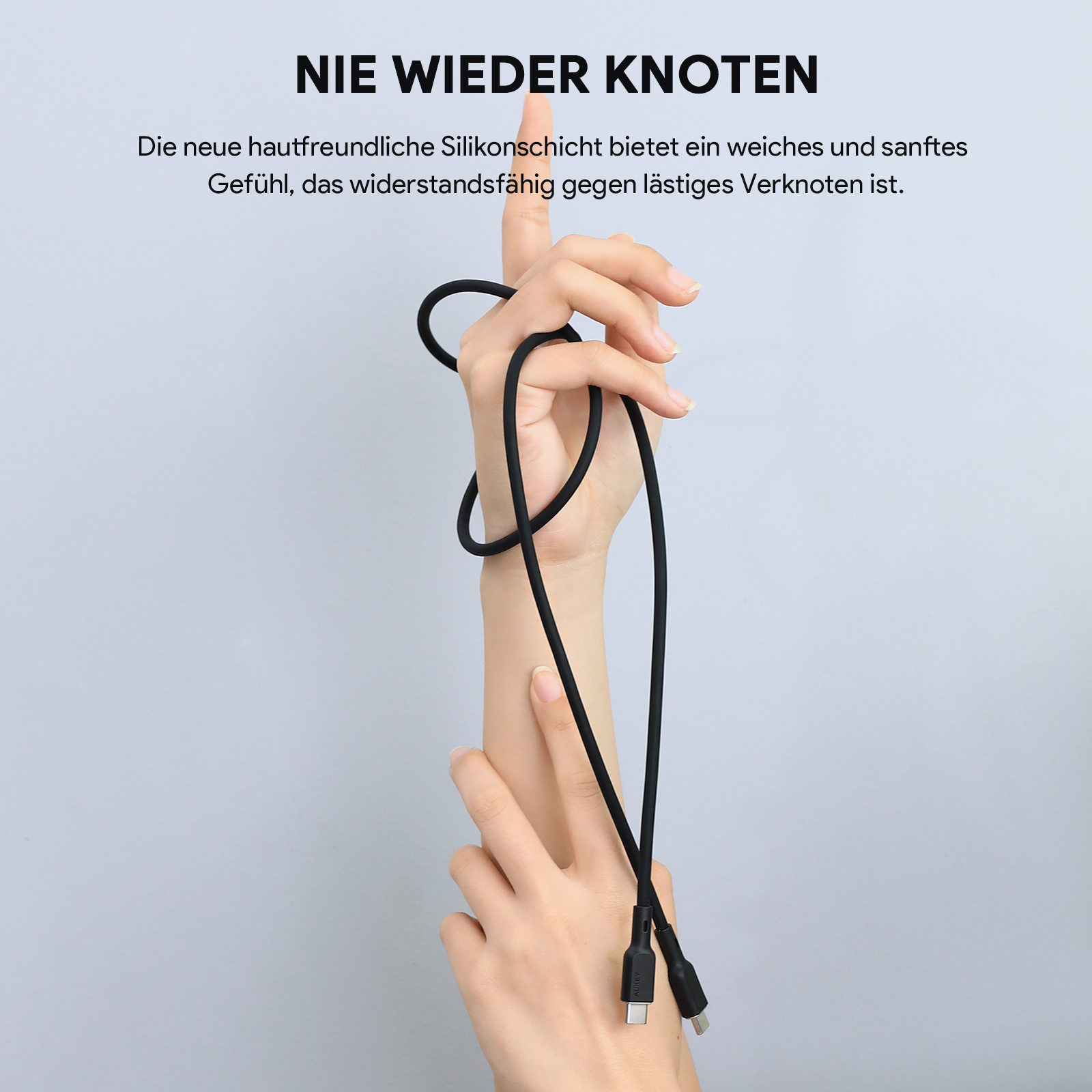 Hände halten ein schwarzes Kabel mit USB-C- und USB-Anschlüssen vor blauem Hintergrund.