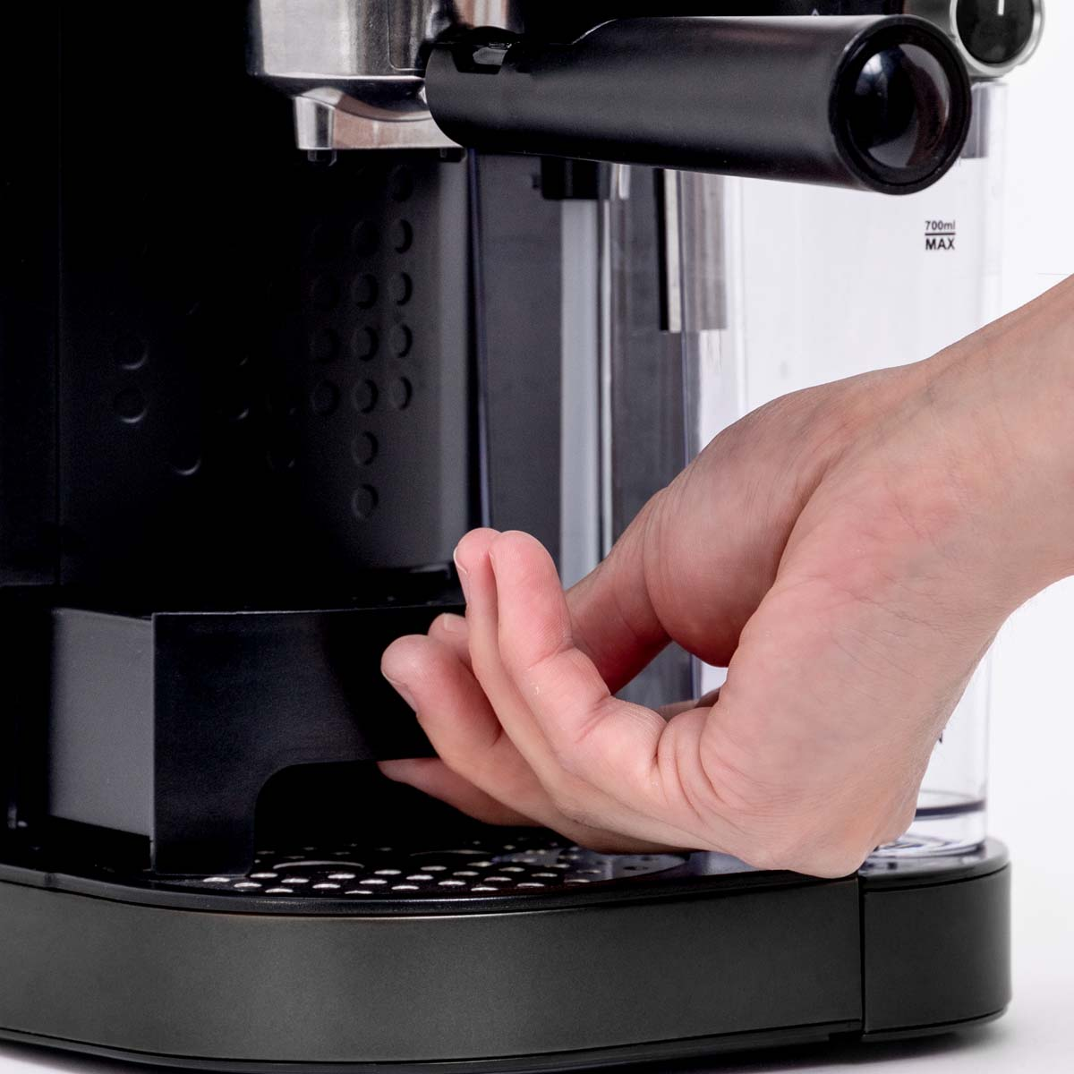 A close-up of a hand operating a black espresso machine. The hand is placing a cup under the dispenser.