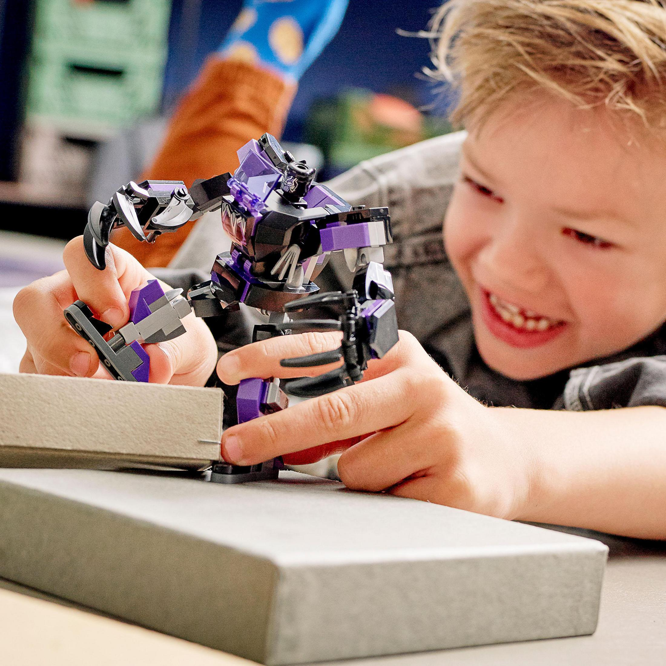 Ein Junge spielt mit einer Lego-Figur, Black Panther. Die Figur ist lila und schwarz.