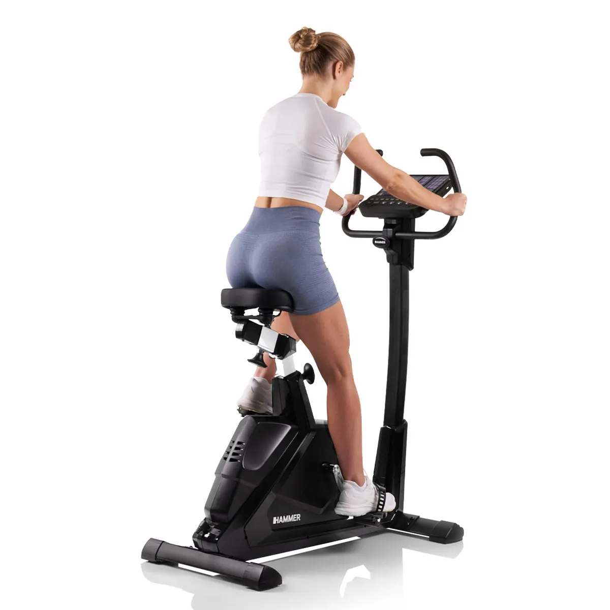 Frau trainiert auf einem schwarzen Heimtrainer.