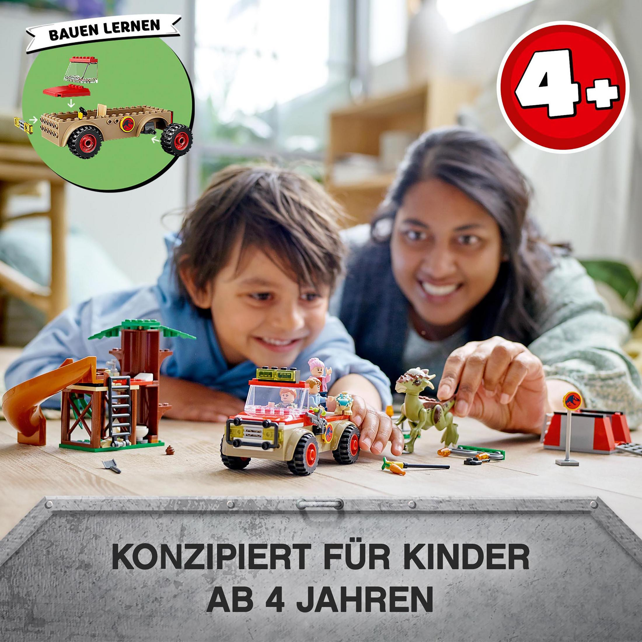 Kinder spielen mit einem Lego-Spielzeugauto und einem Konstruktionsset auf einem Tisch.