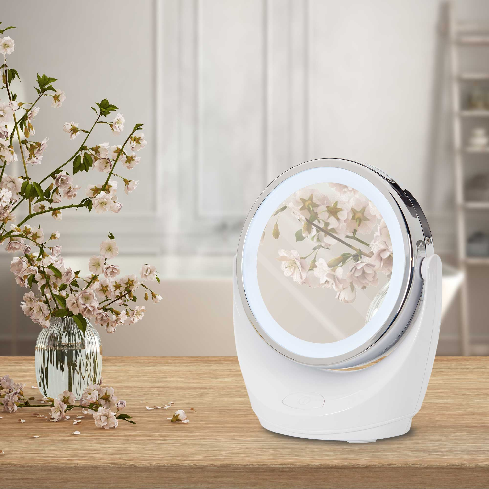 Weißer Schminkspiegel mit floralem Design. Steht auf einem Holztisch mit einer Blumenvase.
