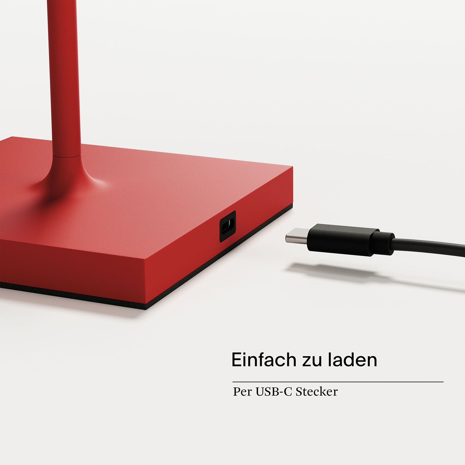 Eine silberne Lampe mit konischem Schirm auf einer dünnen Stange. Der Sockel ist quadratisch. Die Lampe steht auf einem Tisch.