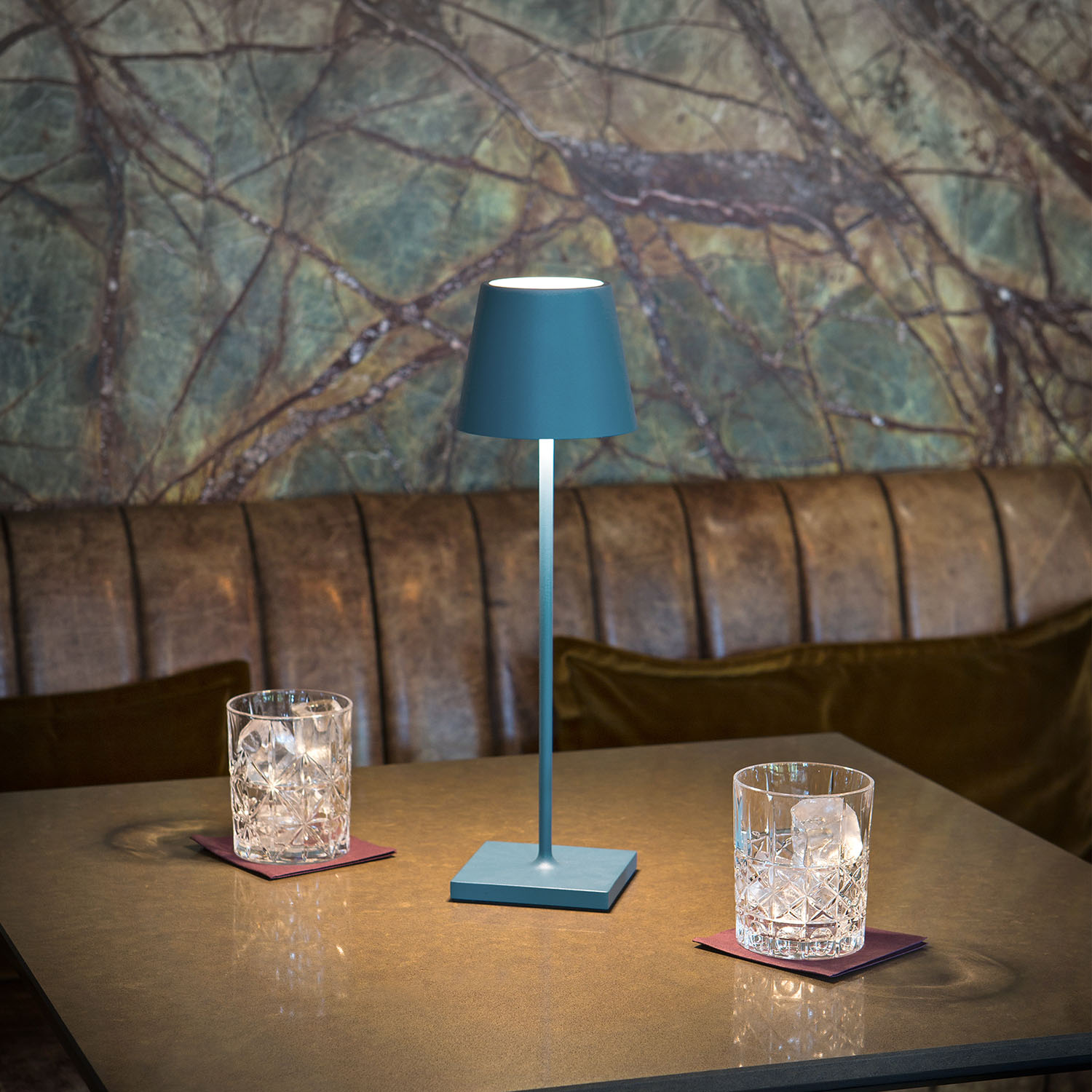 Eine blaue Lampe auf einem Tisch, mit Gläsern und Marmorhintergrund.
