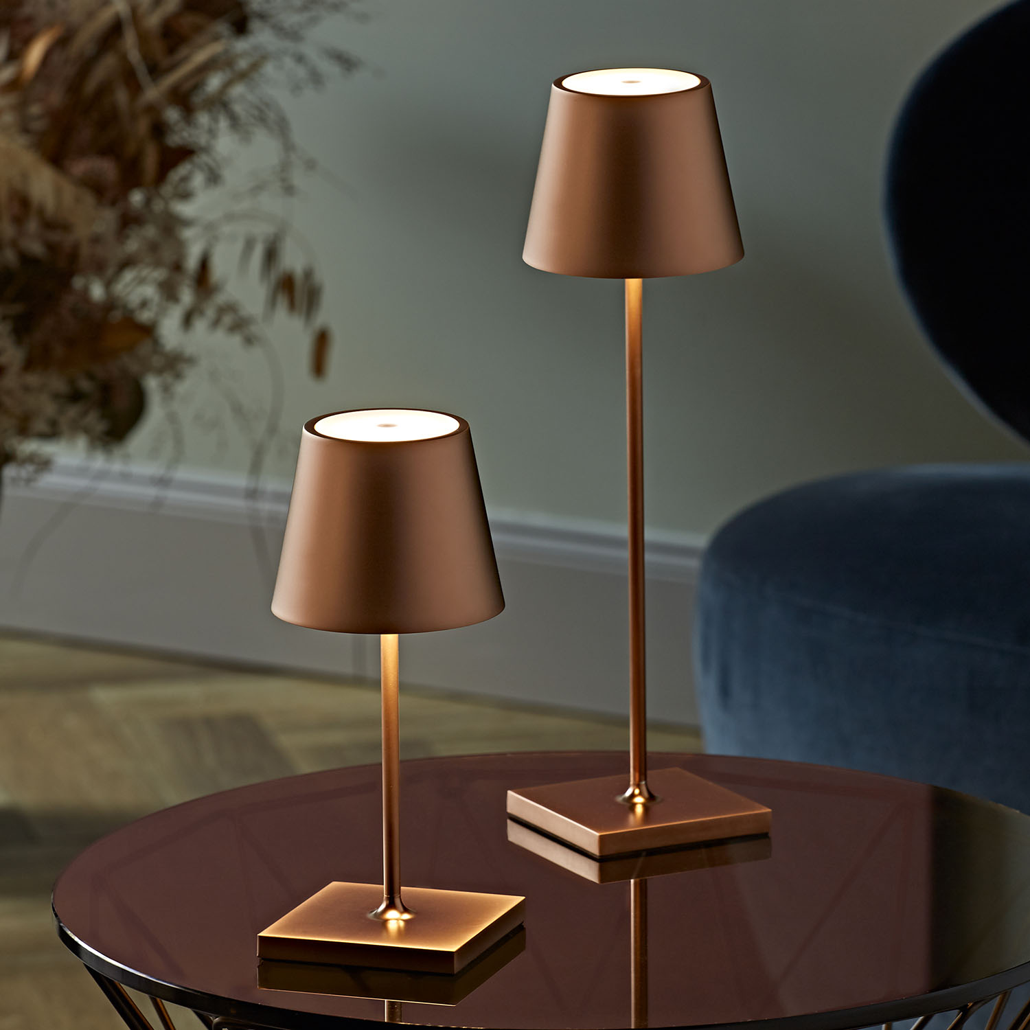 Zwei bronzefarbene Tischlampen. Quadratische Sockel, konische Schirme. Dunkle Oberfläche.