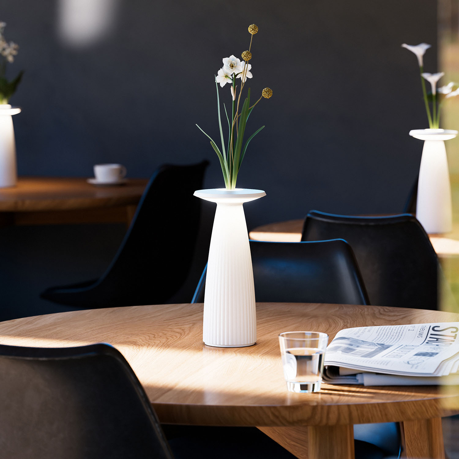 Eine weiße Vase mit Blumen auf einem Holztisch, Stühle und dunkler Hintergrund.