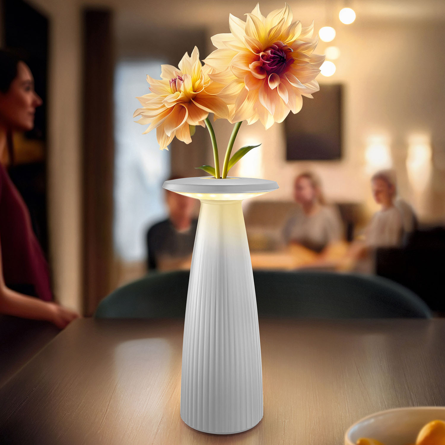Weiße Lampe mit Blumen auf dem Tisch, Personen im Hintergrund unscharf.