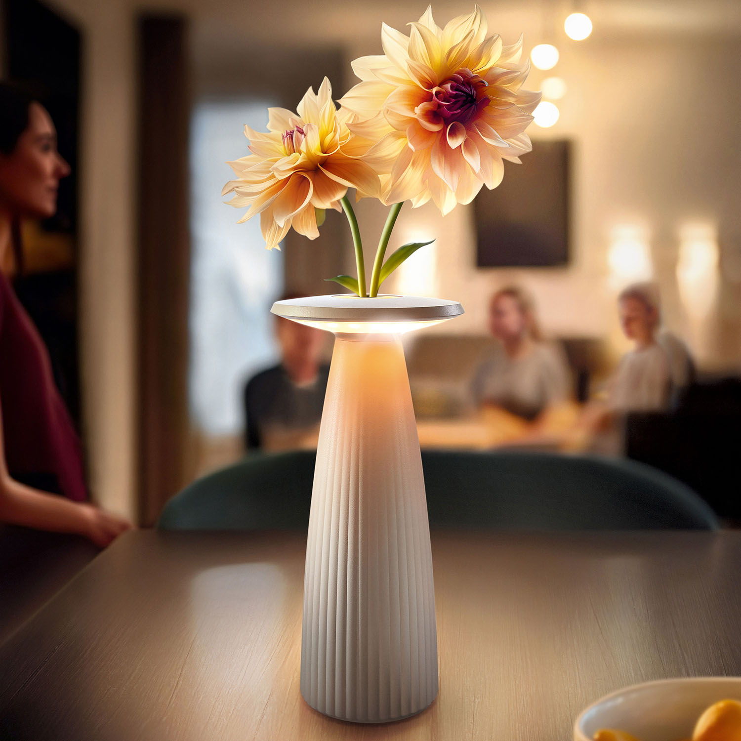 Beleuchtete Lampe mit Blumen auf einem Tisch. Personen im Hintergrund unscharf.