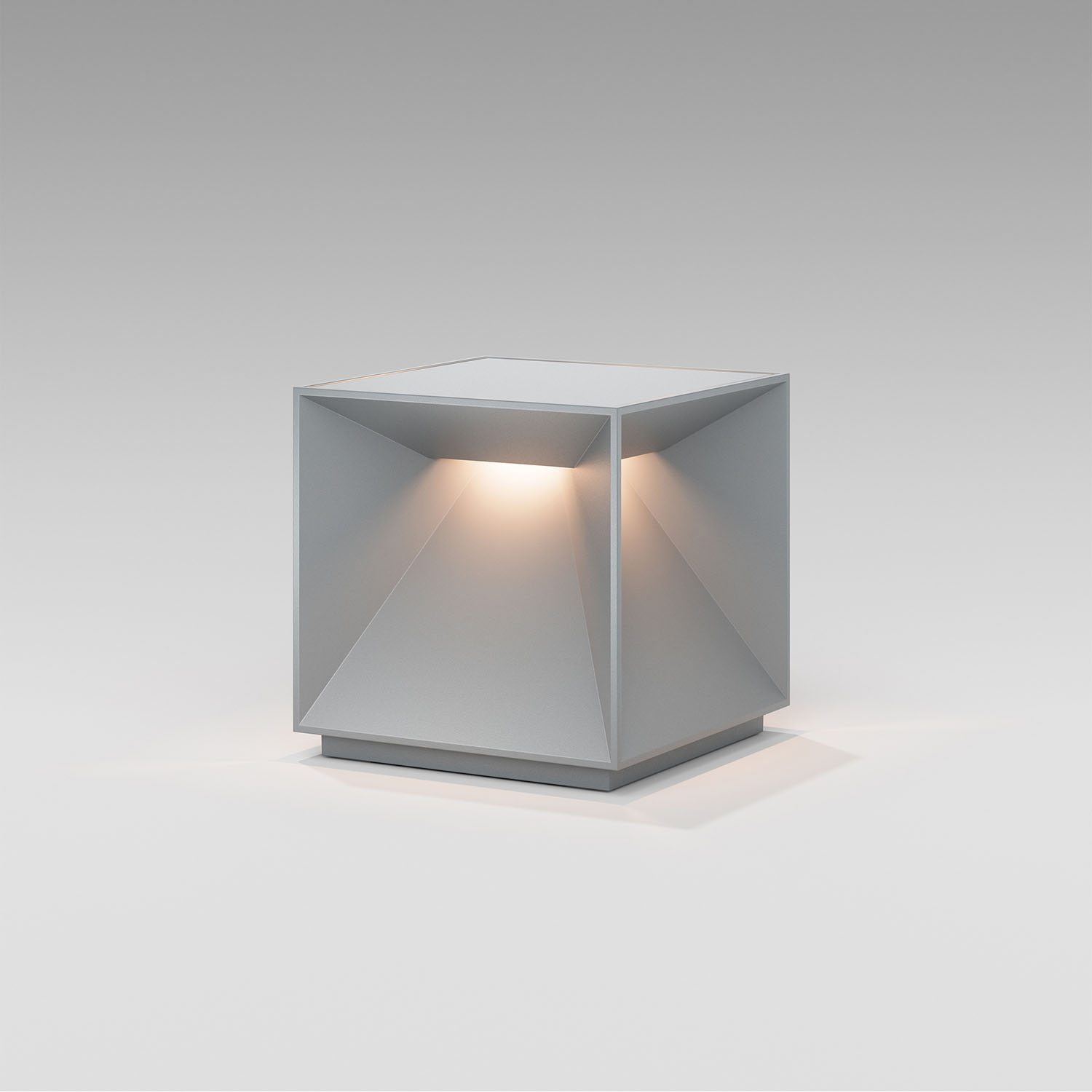 Eine graue, würfelförmige Lampe mit beleuchtetem Innenraum, die auf einer weißen Oberfläche steht.