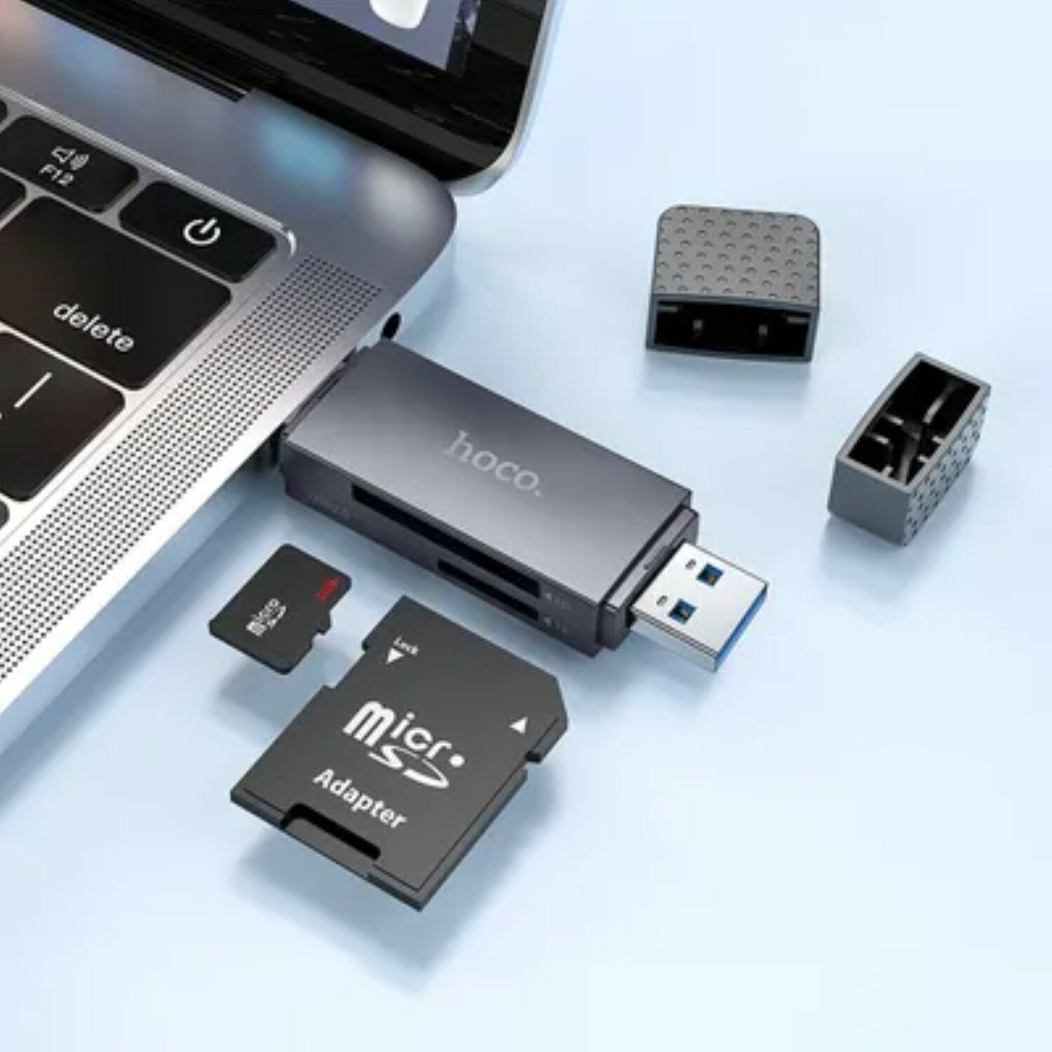 Silberner USB-Kartenleser mit SD-Karten und Adaptern, in der Nähe einer Laptop-Tastatur.