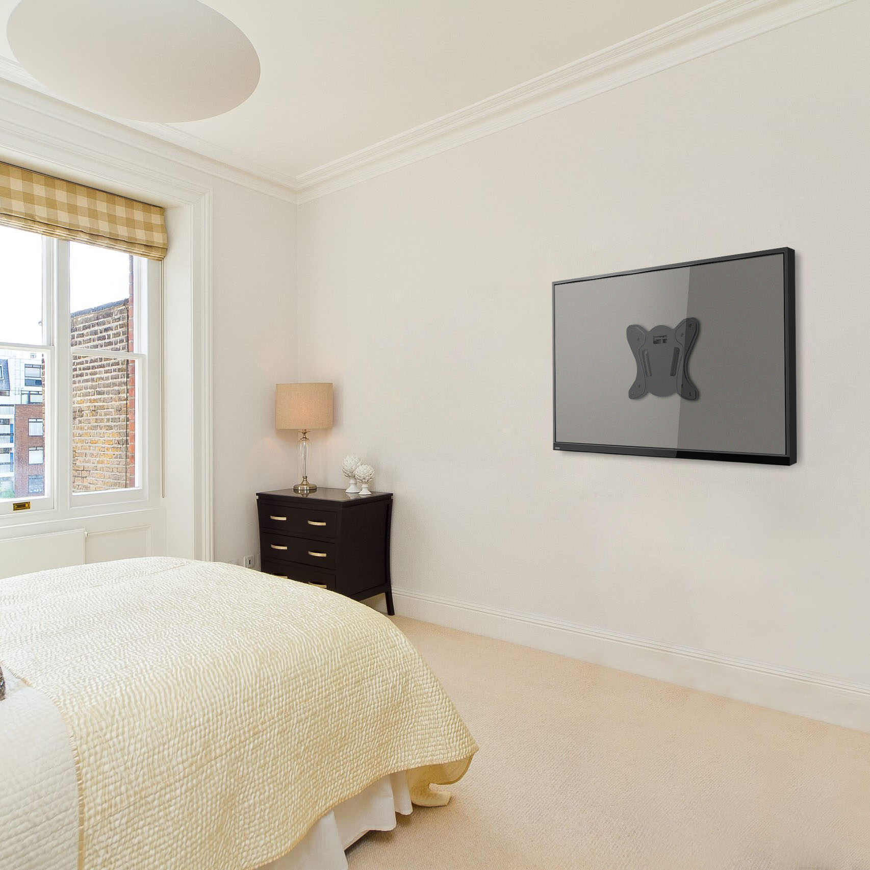 Dormitorio con TV montada en la pared. Se ve una cama, una cómoda y una ventana.