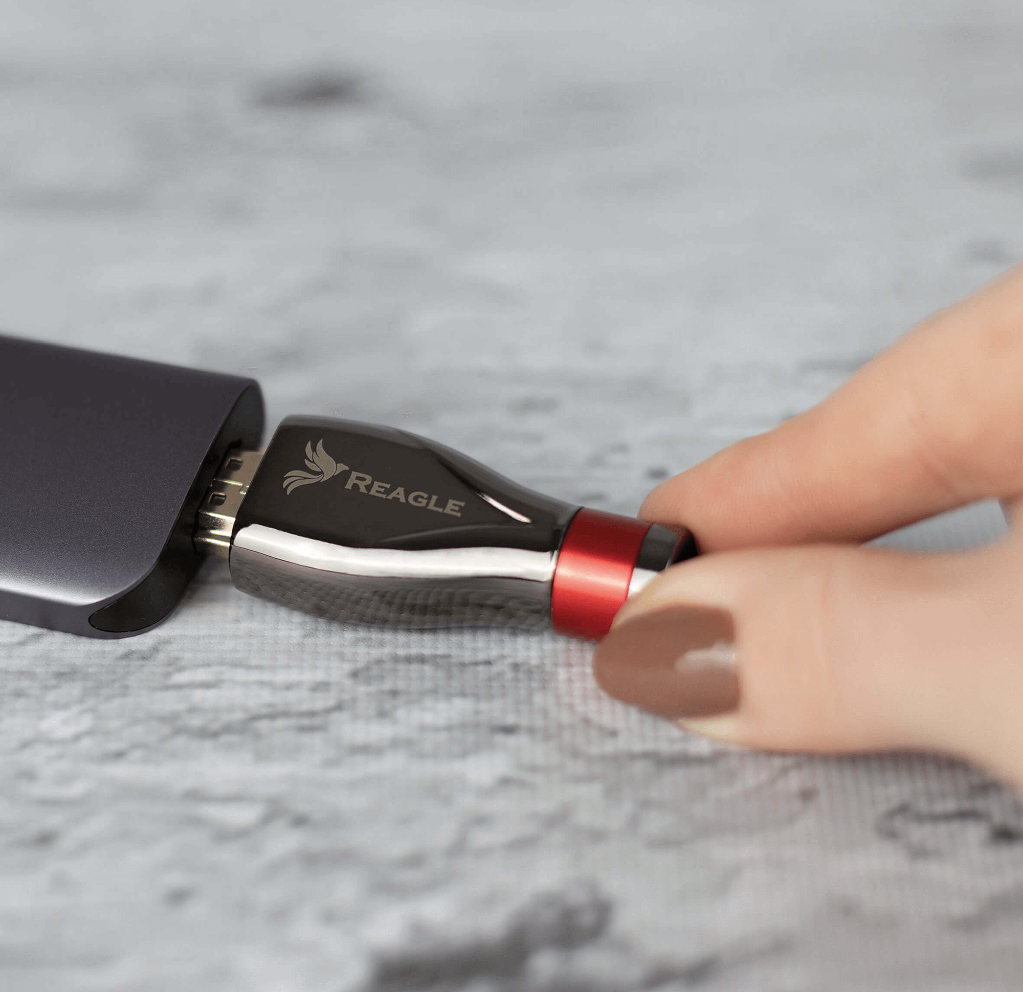 Ręka wkładająca czarno-czerwoną przejściówkę USB-C do urządzenia.