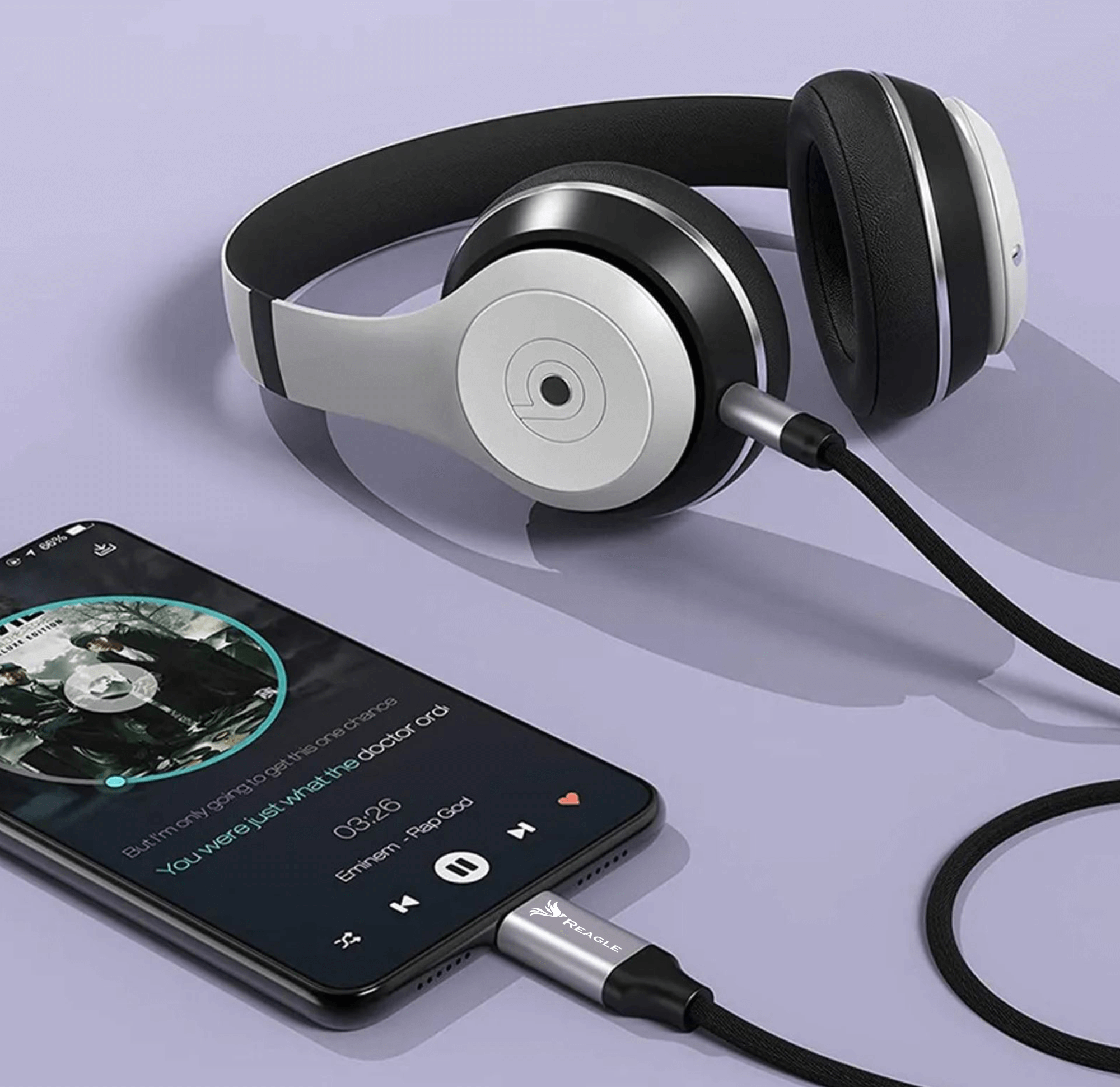 Słuchawki podłączone do telefonu odtwarzającego muzykę. Czarny kabel, fioletowe tło.