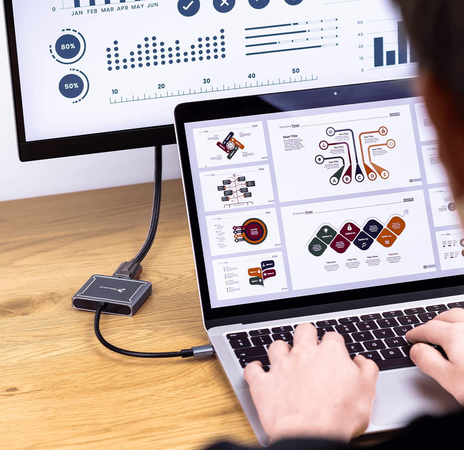 Osoba pracująca na laptopie podłączonym do monitora przez hub, z wykresami na ekranie.