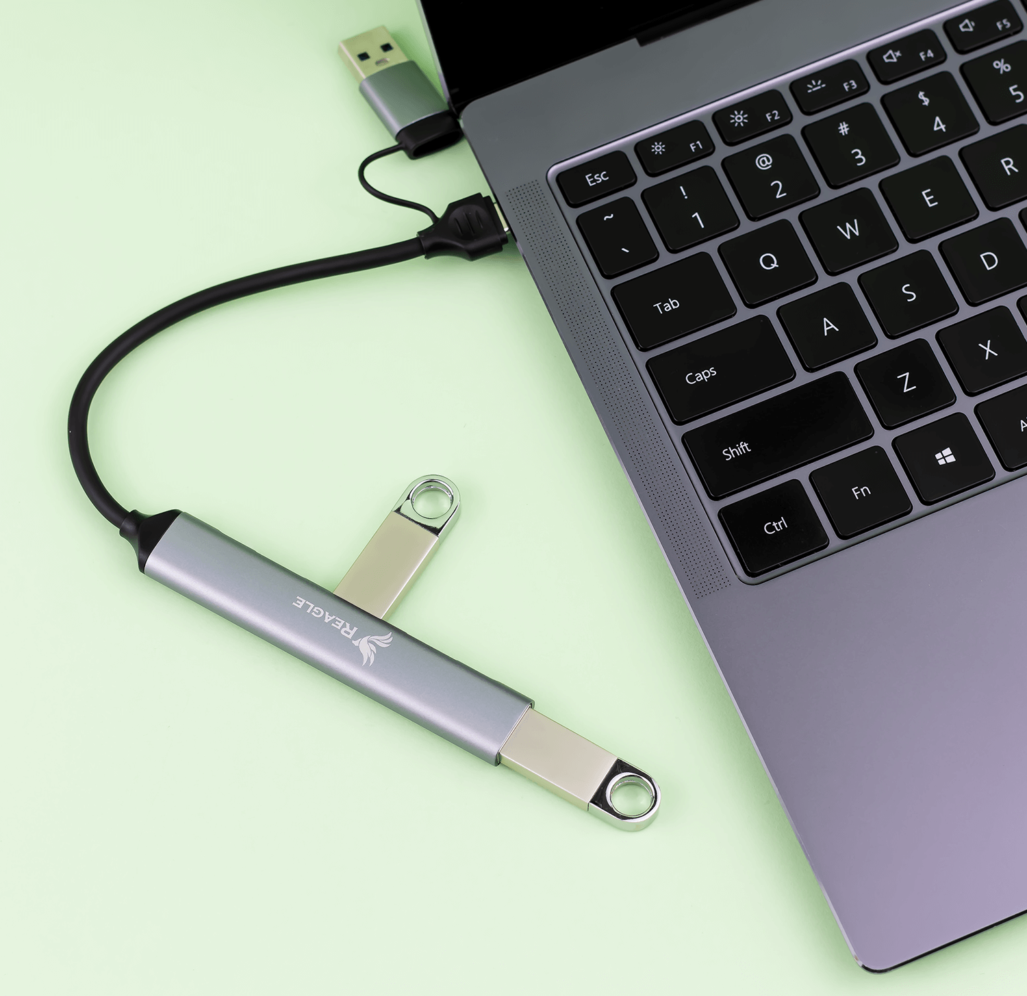 Srebrny hub USB podłączony do laptopa z pendrivem.