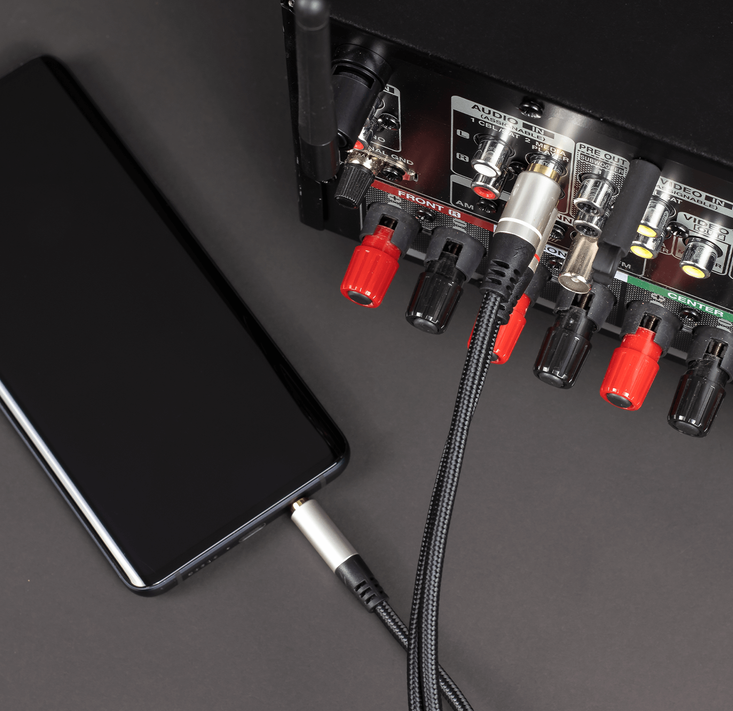 Telefon mit Kabel an Audio-Receiver angeschlossen. Schwarzes Telefon, Receiver und schwarzer Hintergrund.