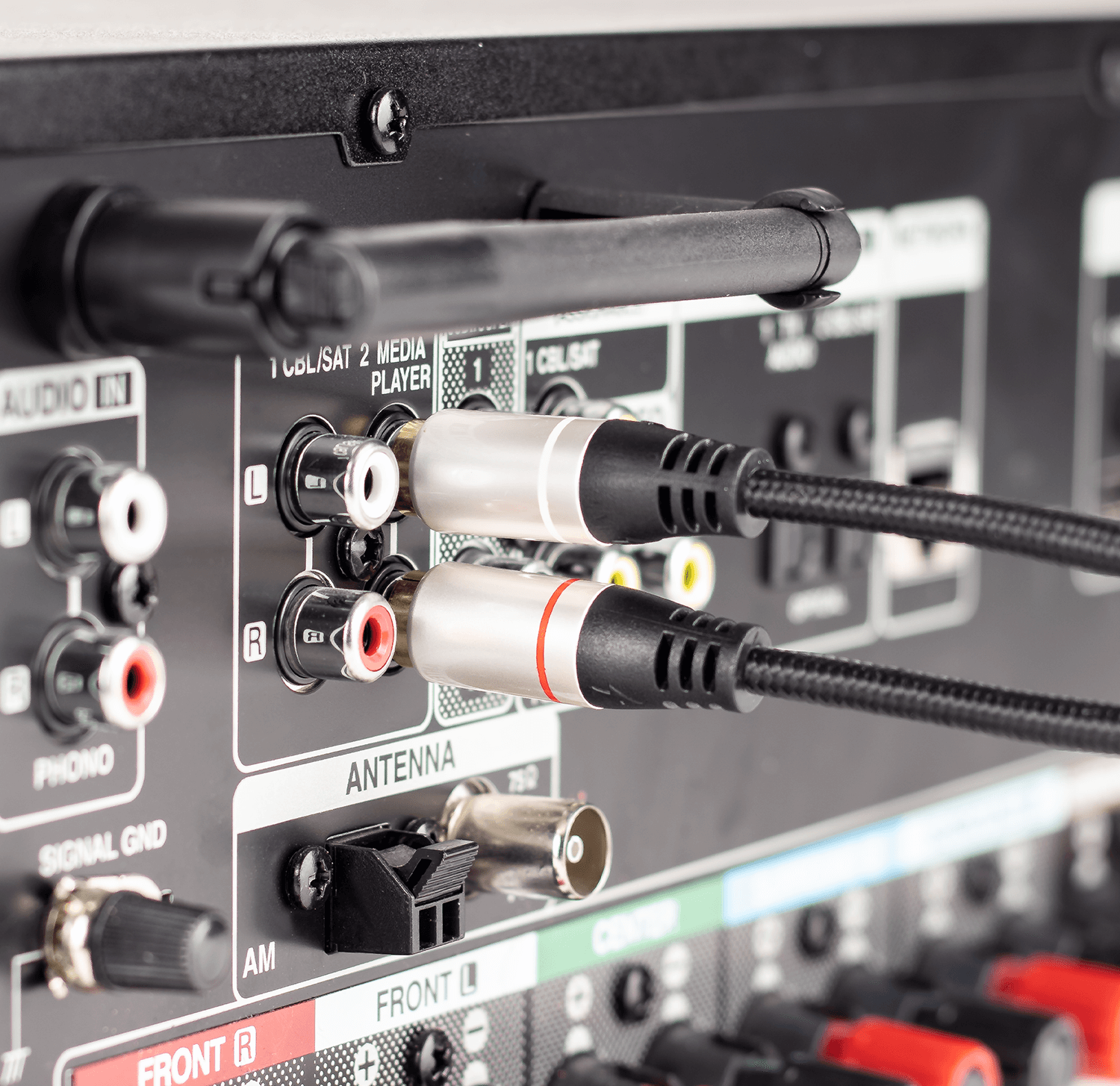 Nahaufnahme der Rückseite eines Audio-Receivers mit angeschlossenen Cinch-Kabeln und anderen Anschlüssen.