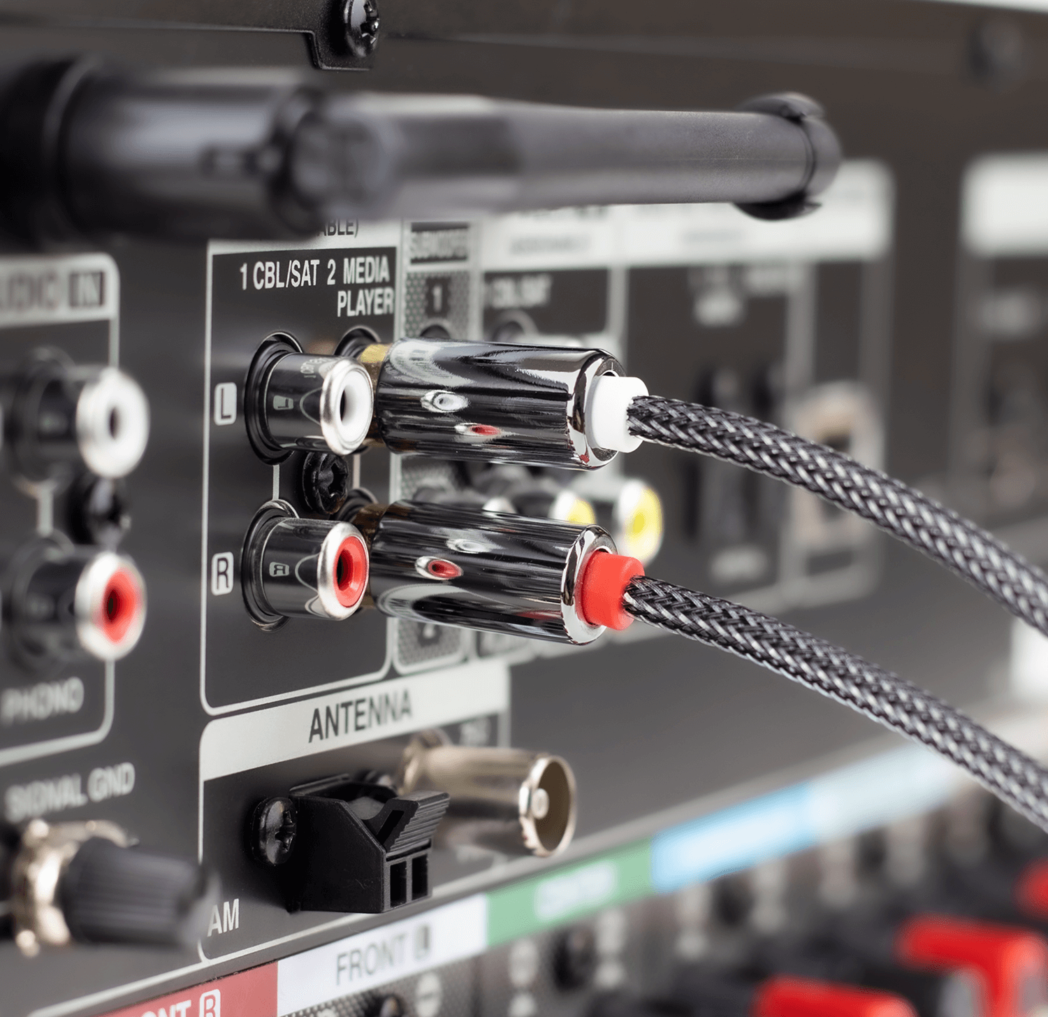 Zbliżenie kabli RCA podłączonych do odbiornika. Czarne i srebrne kable z czerwonymi i białymi złączami.