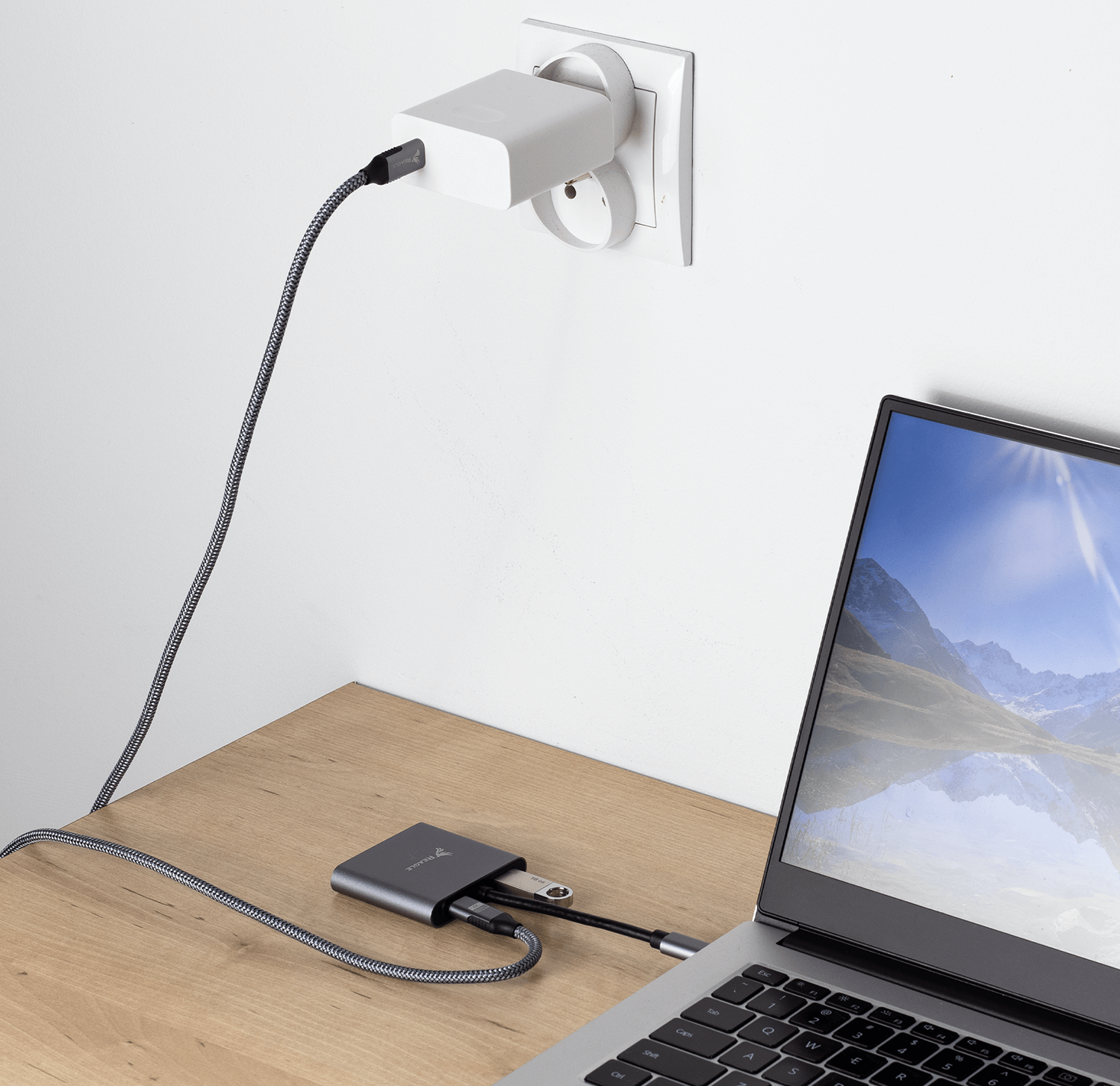 Laptop podłączony do huba, podłączony do gniazdka ściennego.