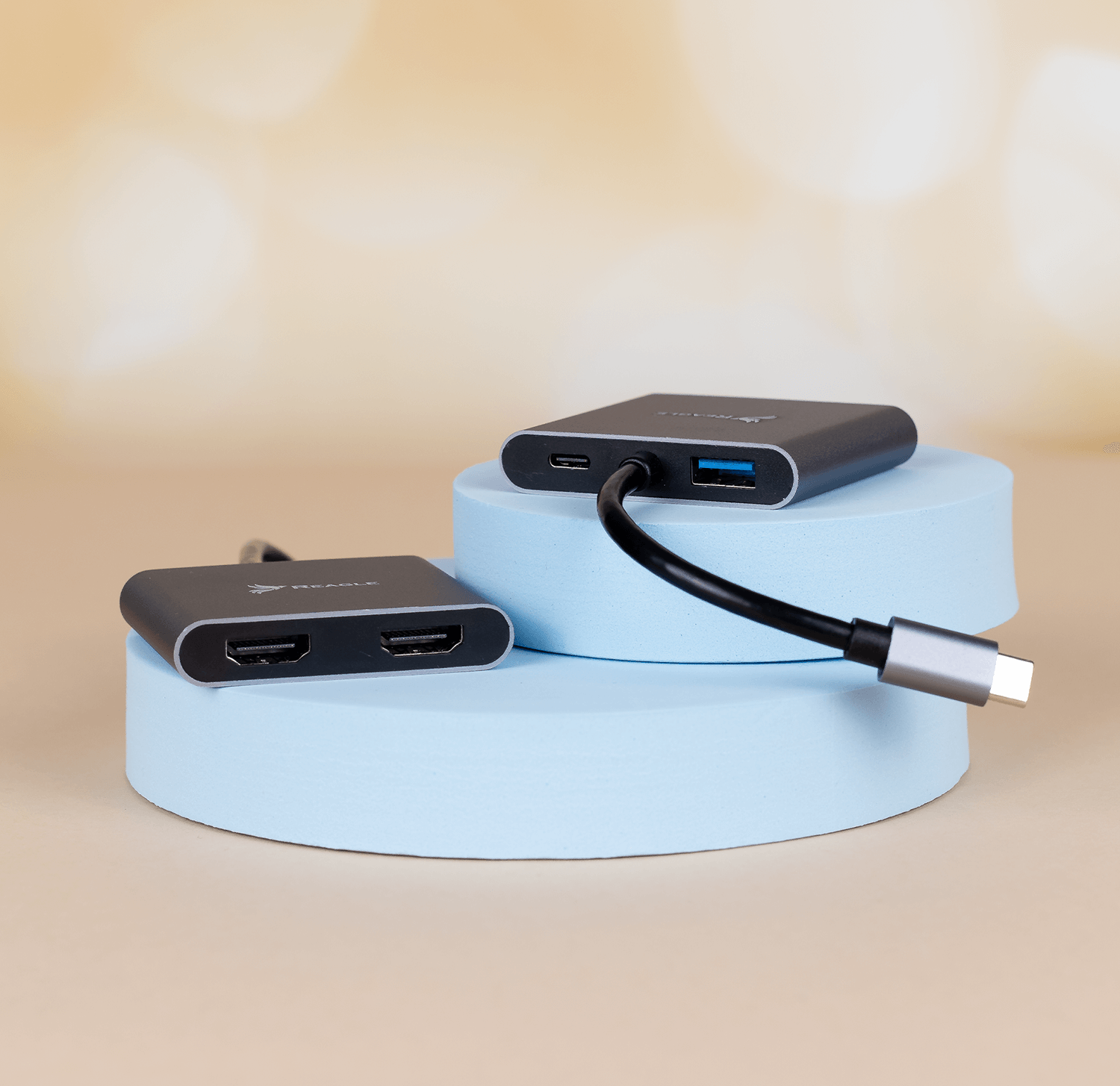 Dwa czarne huby USB na niebieskich platformach. Tło jest rozmyte, jasnobrązowe.