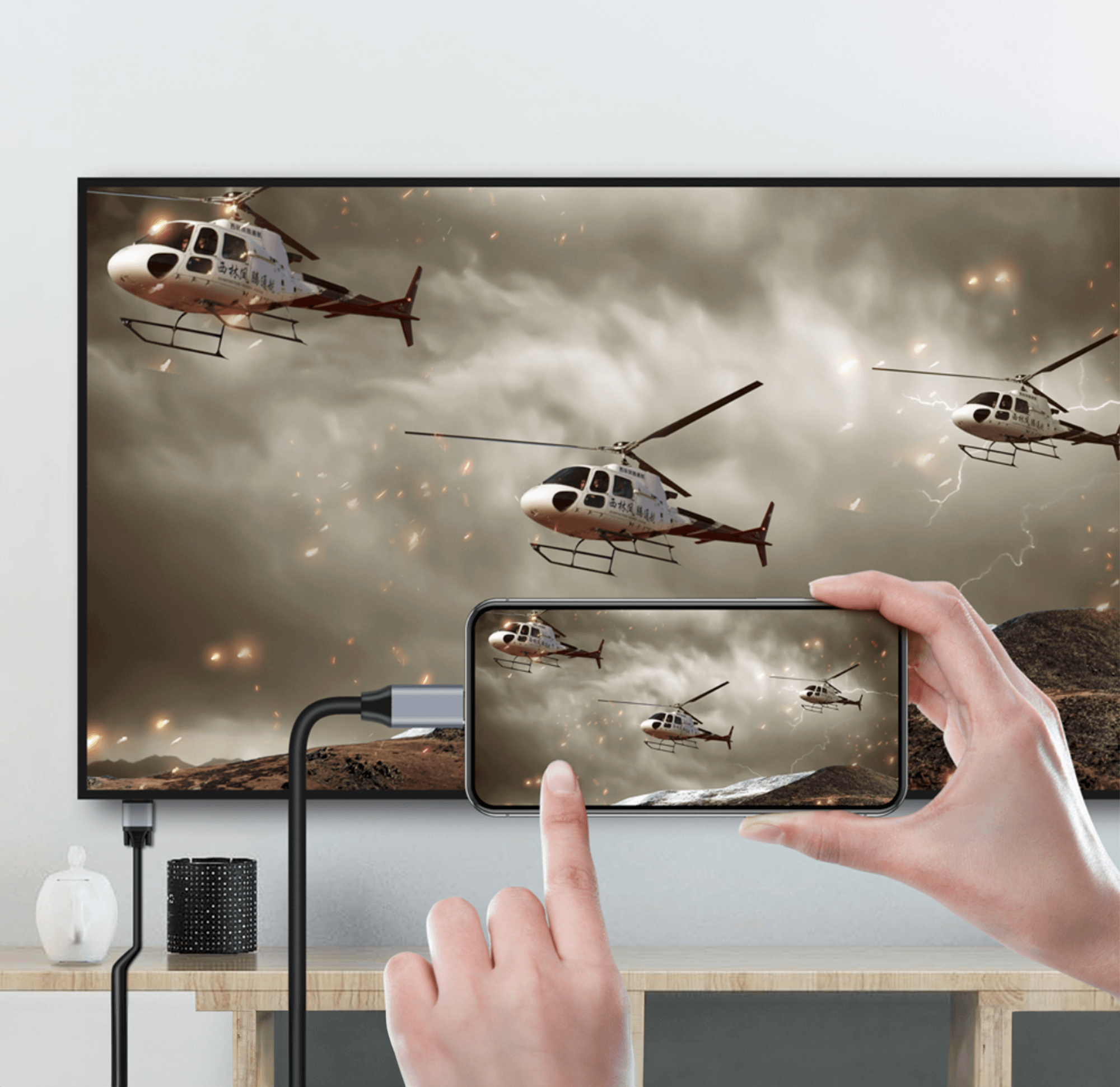 Osoba trzymająca telefon pokazujący wideo z helikopterami na tle zachmurzonego nieba.