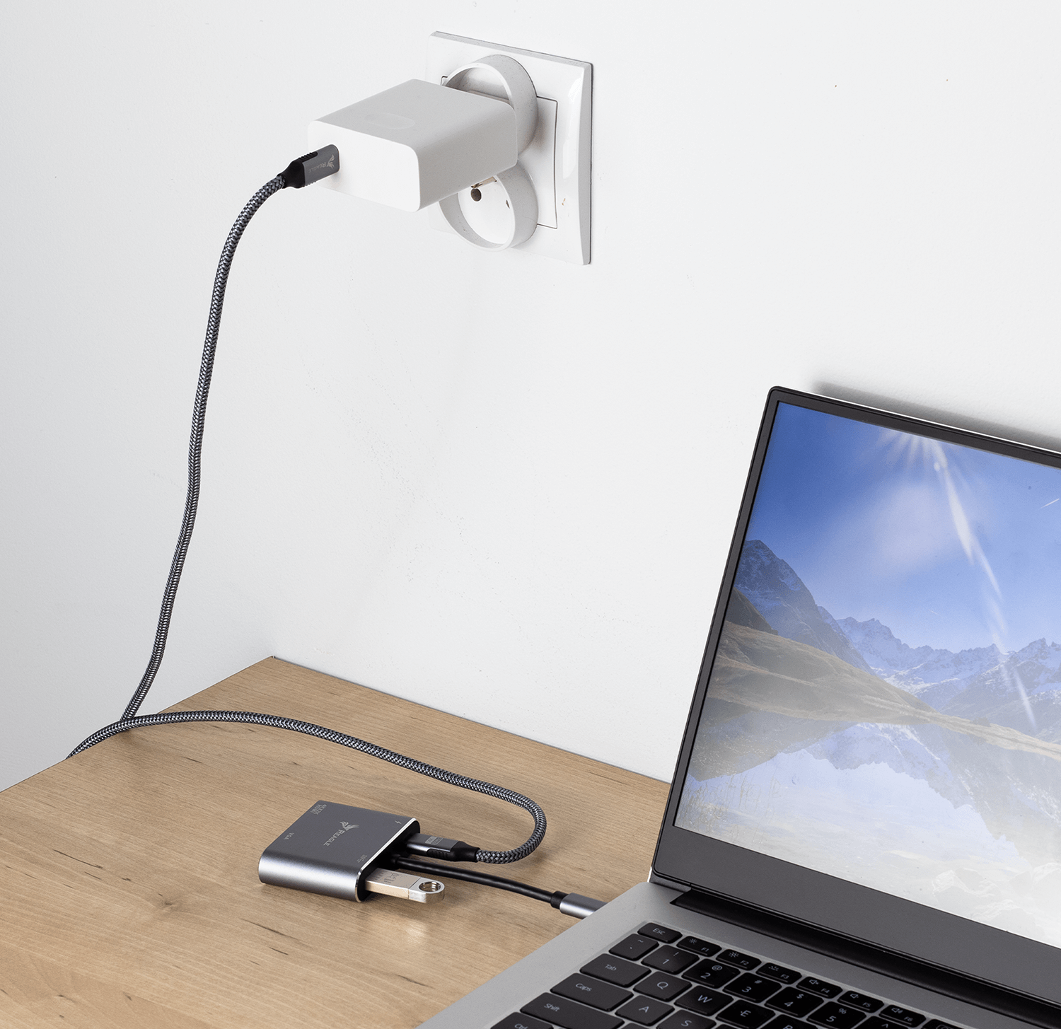 Hub podłączony do laptopa i gniazdka ściennego, z włożonym pendrivem.