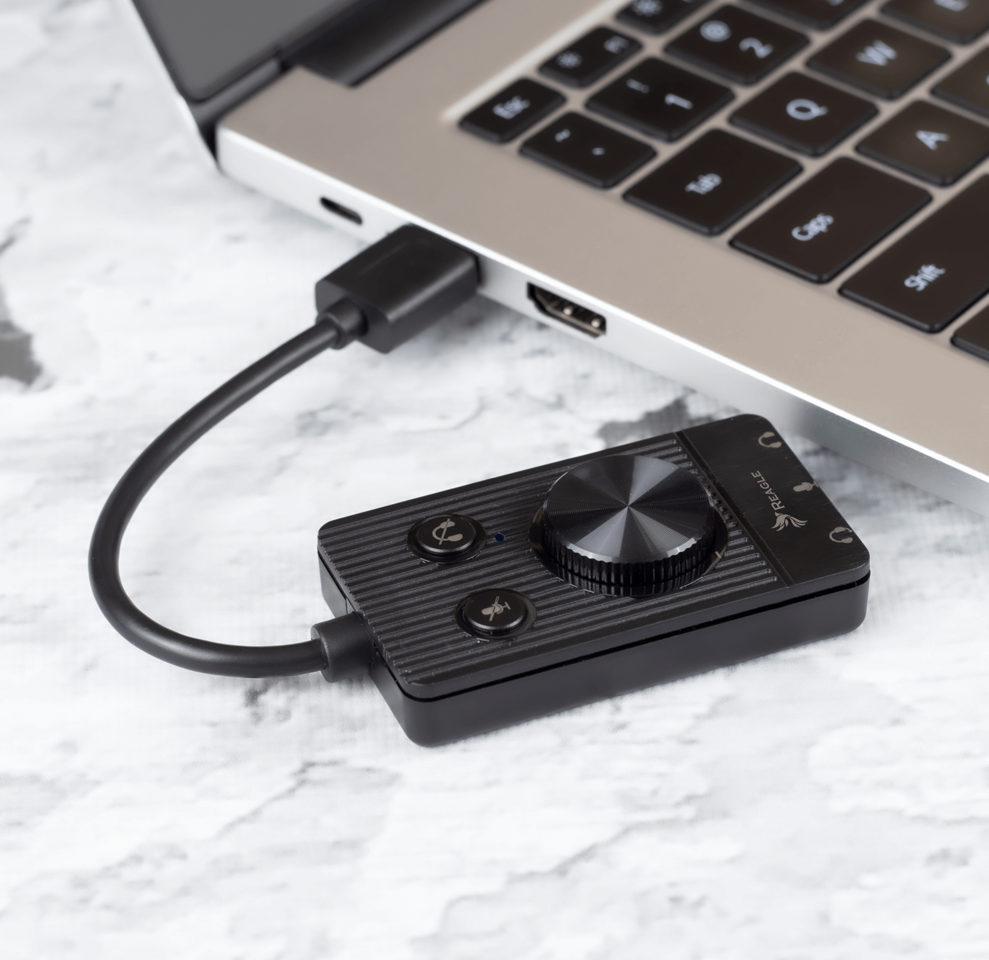 Czarny interfejs audio podłączony do laptopa. Ma przyciski, pokrętło i kabel USB.