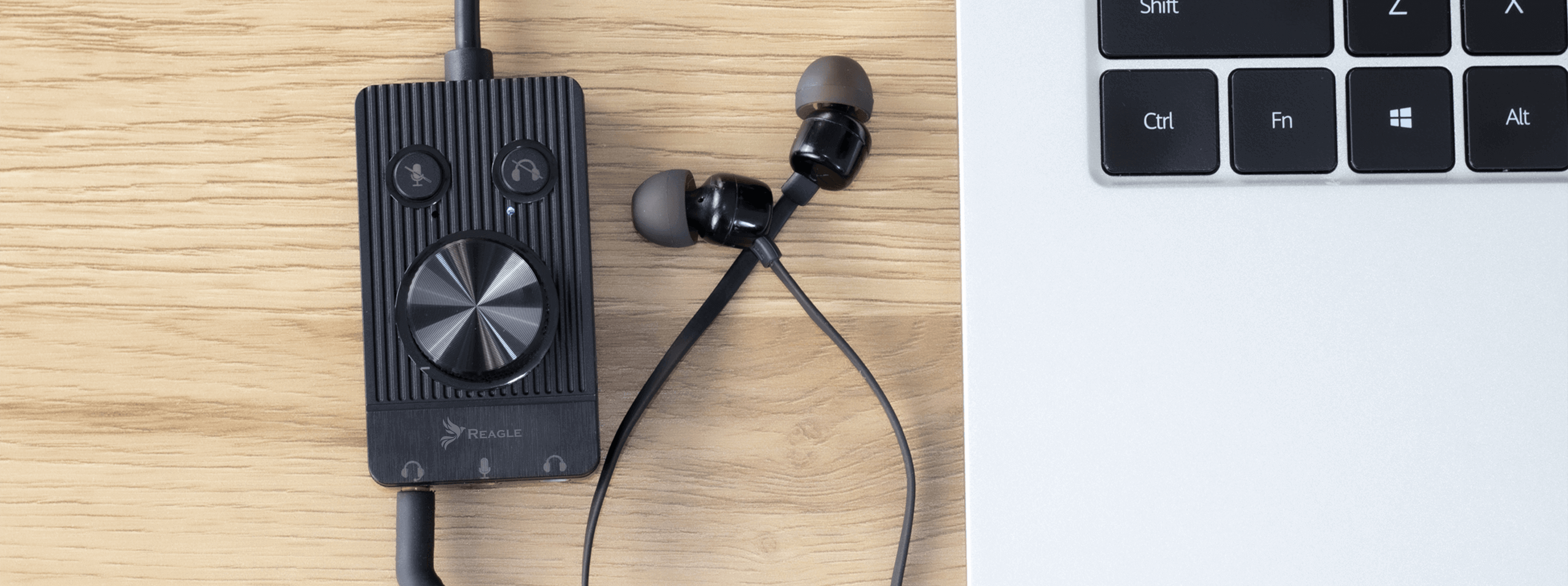 Czarny interfejs audio i słuchawki na drewnianym biurku. Laptop w tle.