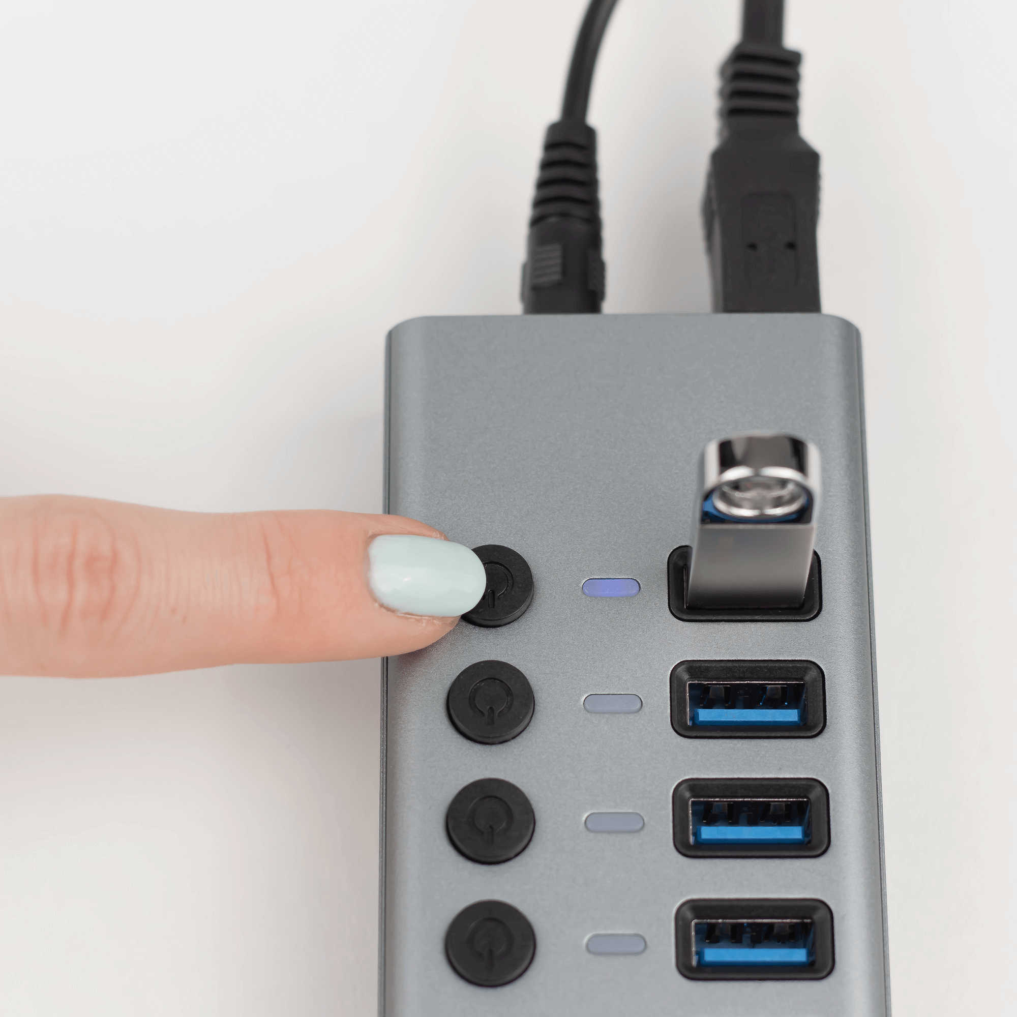 Ręka naciskająca przycisk na hubie USB. Włożony pendrive.