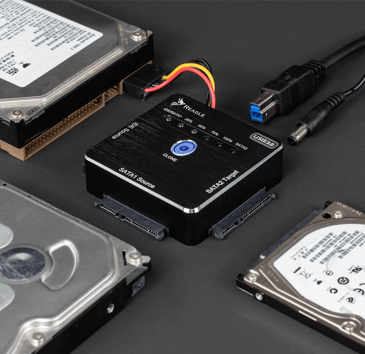 Czarne urządzenie z trzema dyskami twardymi. Podłączony kabel USB. Ciemne tło.