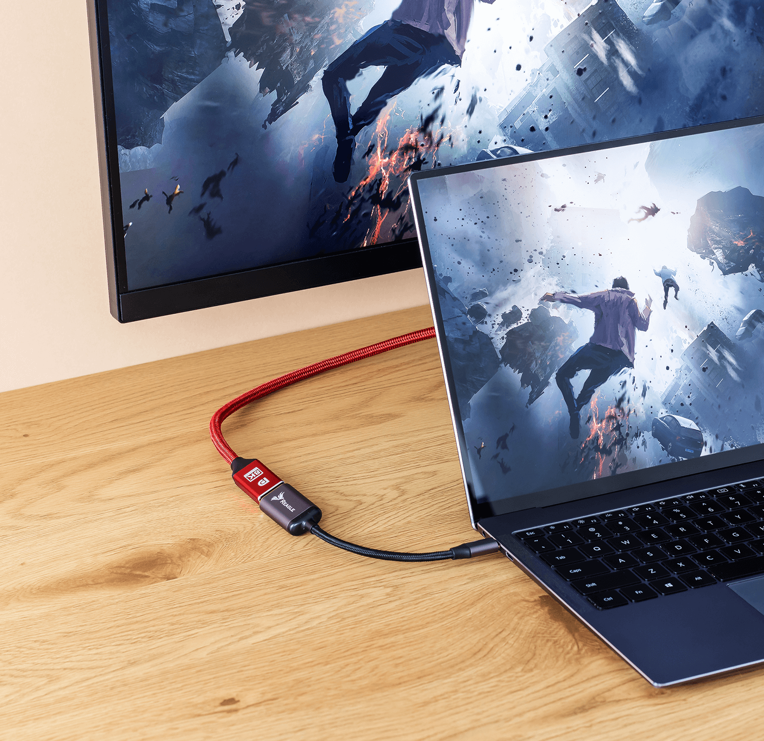 Laptop podłączony do monitora za pomocą czerwono-czarnego kabla HDMI na drewnianym biurku. Wyświetlana jest gra.