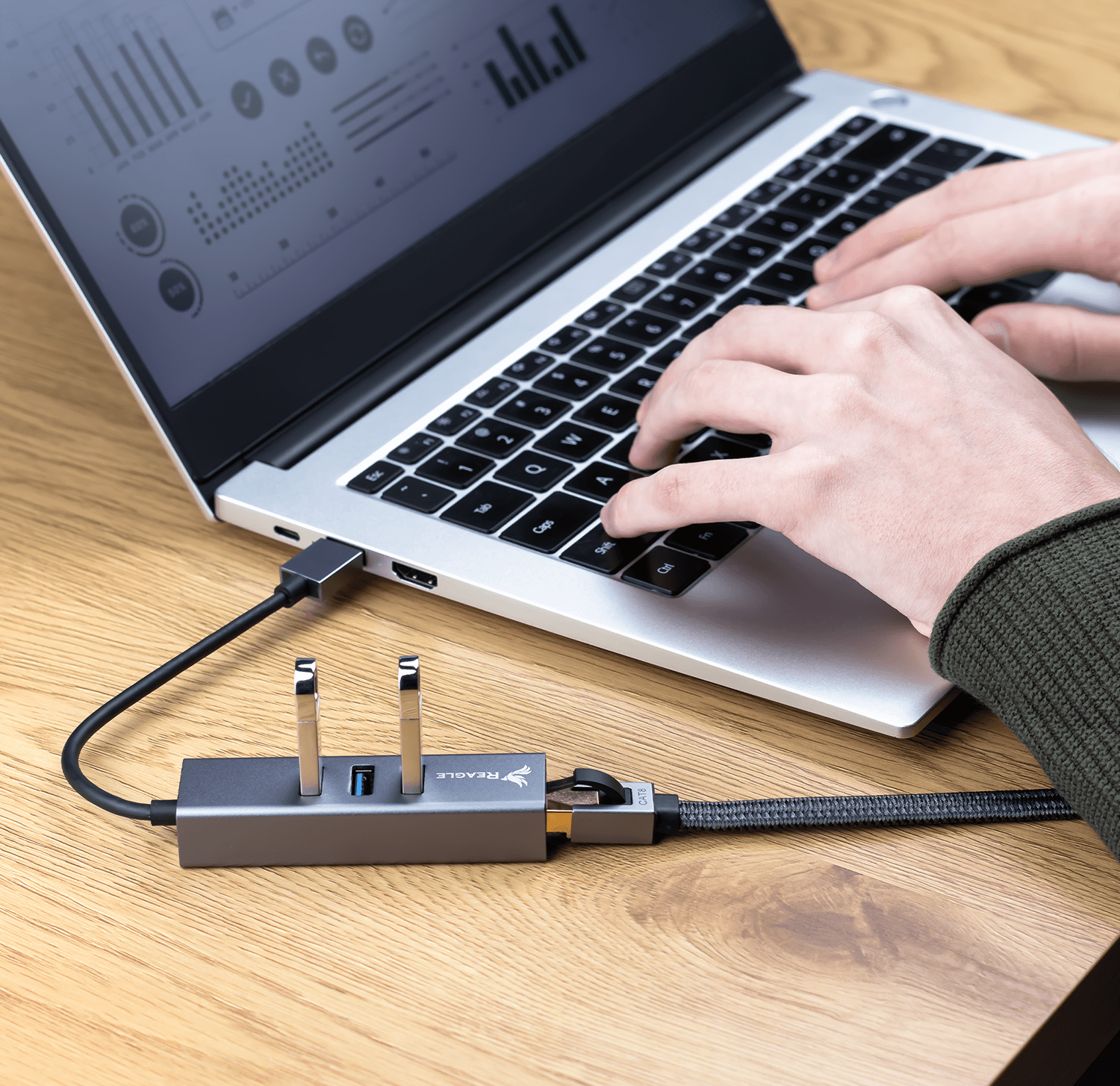 Ręce piszące na klawiaturze laptopa. Hub USB jest podłączony do laptopa.