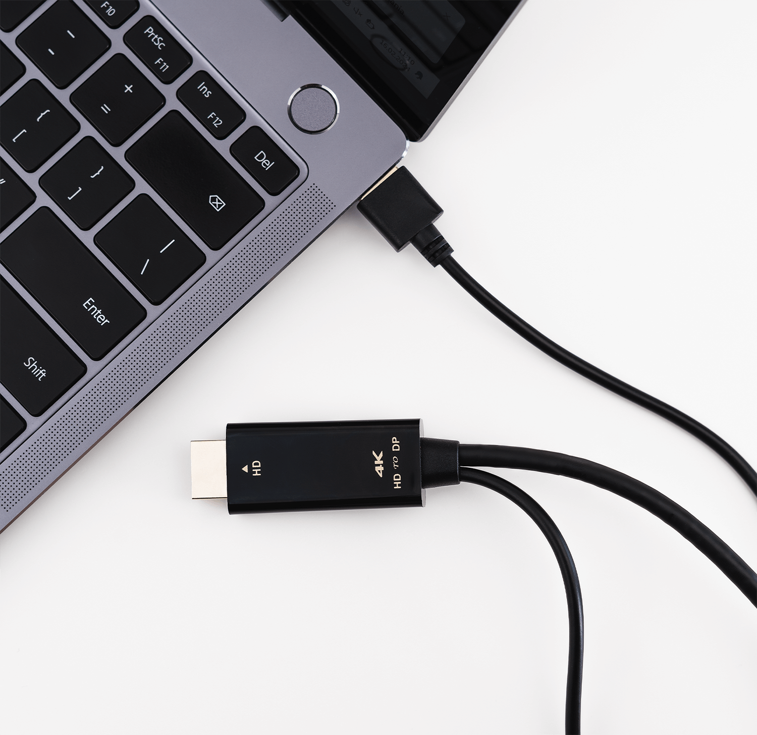 Laptop ma podłączony czarny kabel. Kabel rozdziela się na dwa złącza, jedno HDMI, jedno DP.