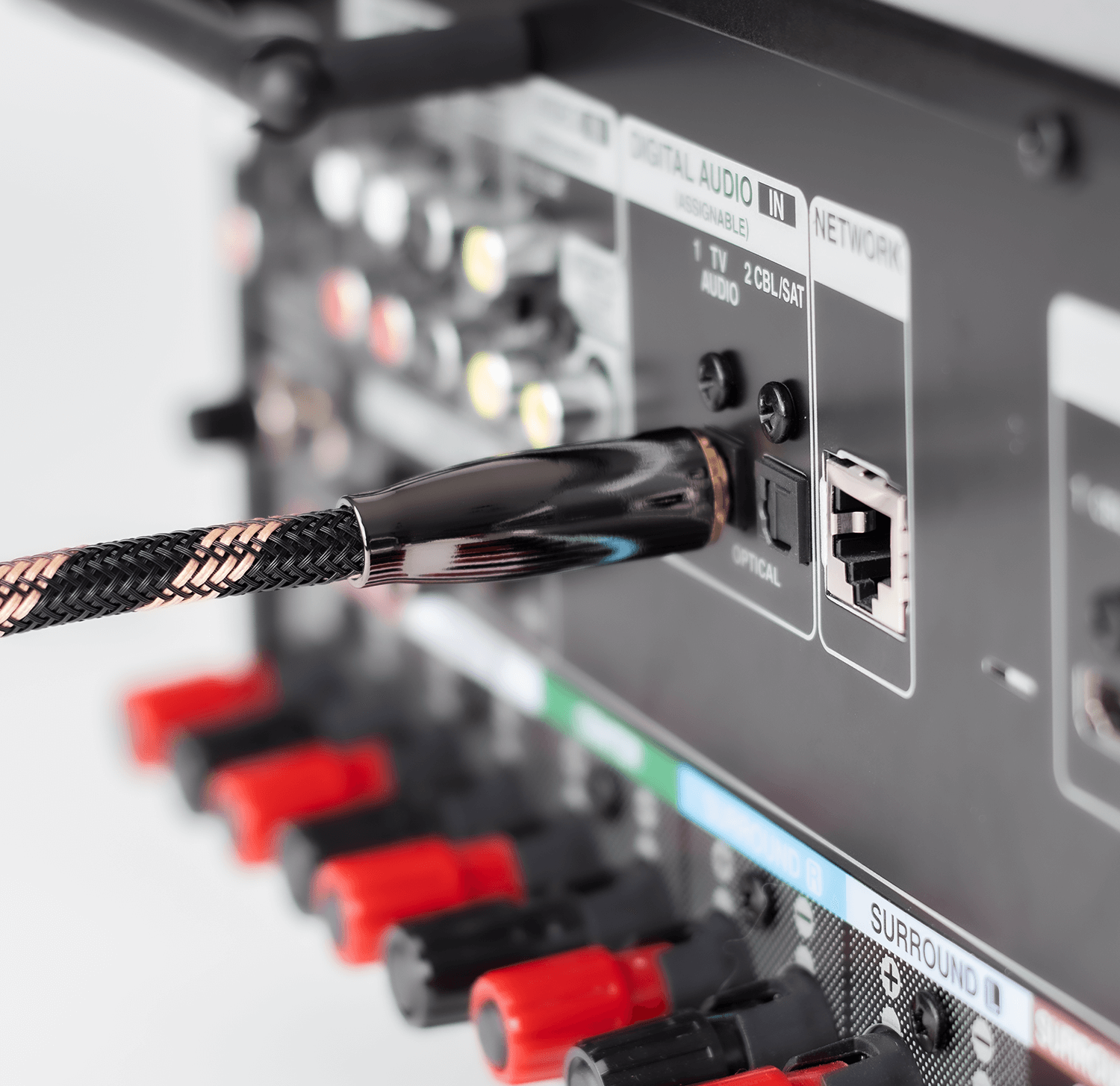 Zbliżenie tyłu odbiornika z podłączonym czarno-miedzianym kablem. Kilka portów i złączy.