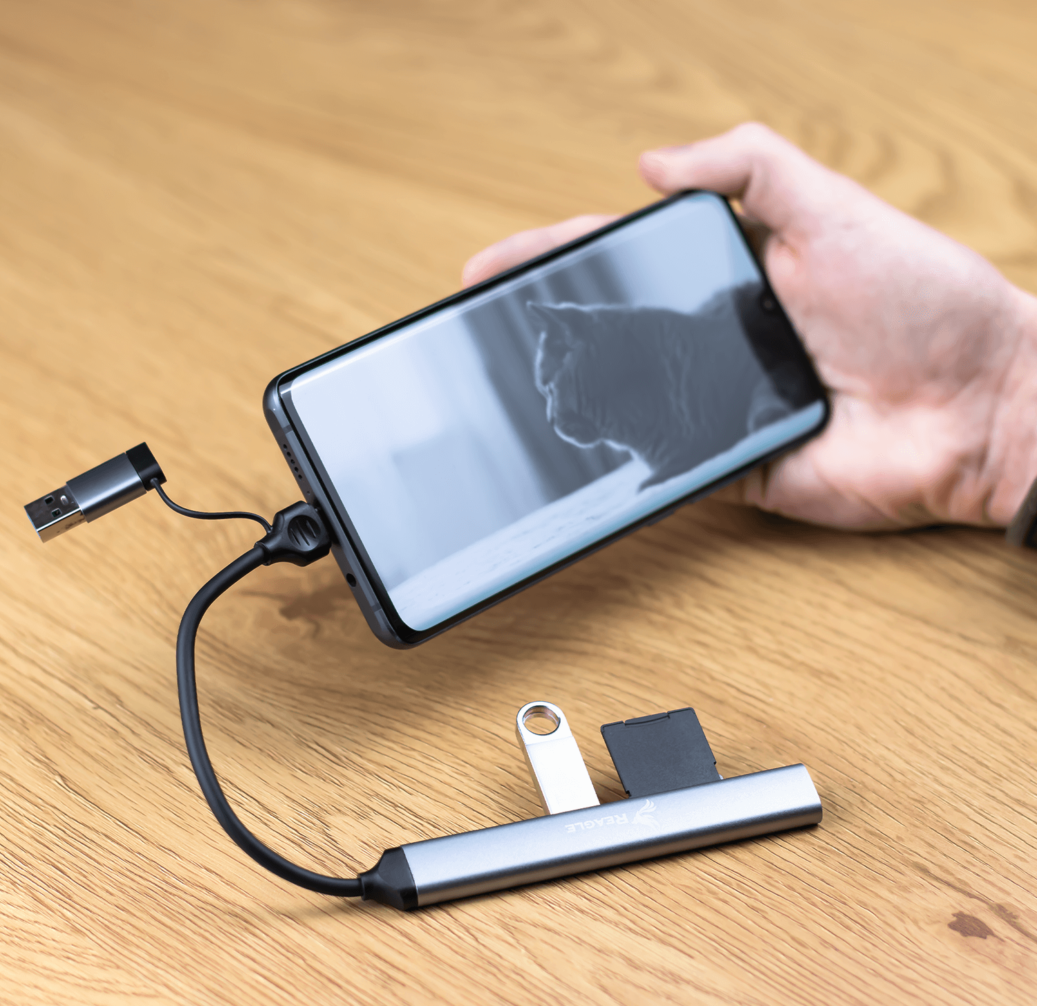 Mano che tiene un telefono collegato a un hub USB. Hub con slot USB.