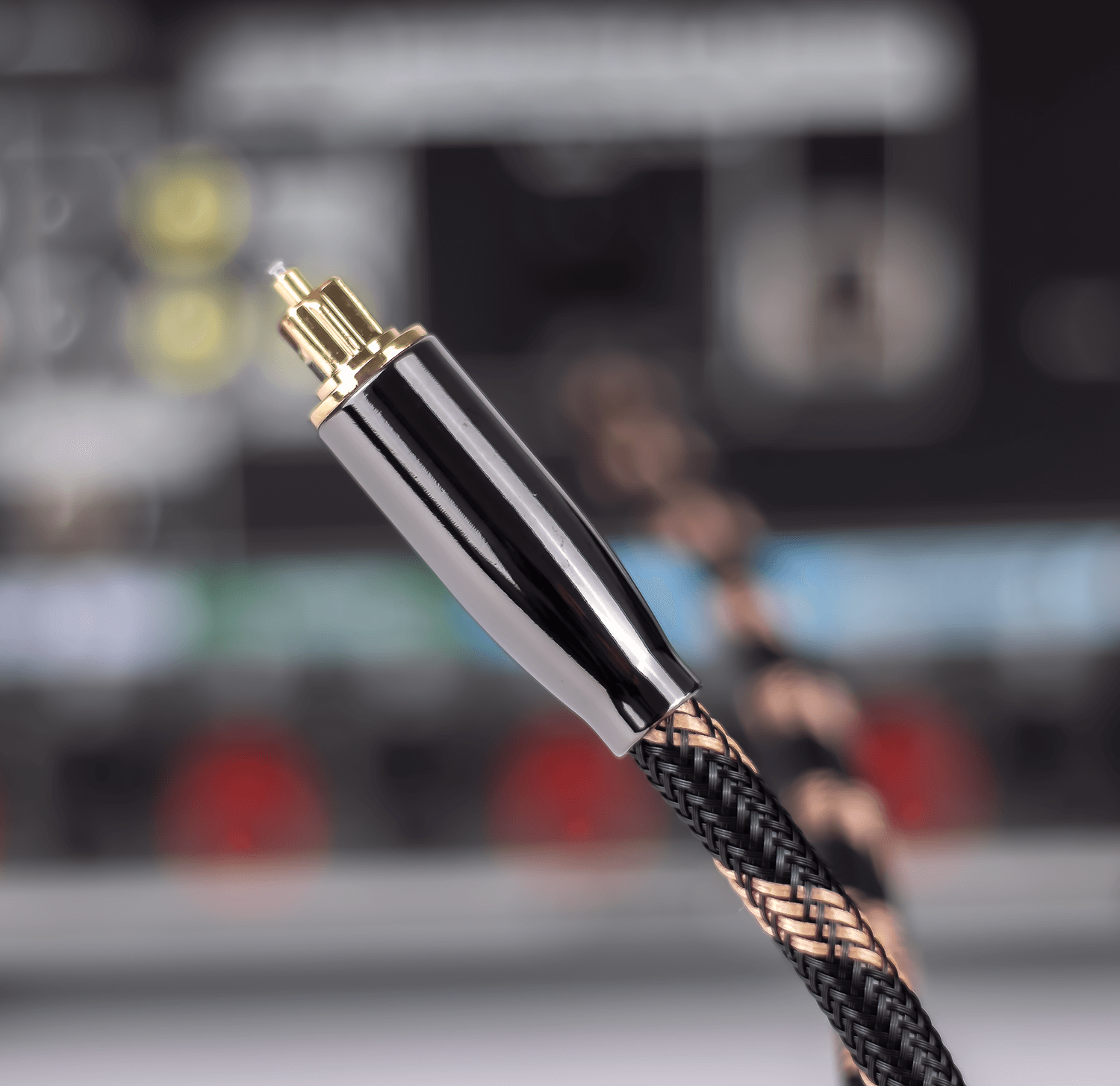 Czarno-złoty kabel audio z metalową końcówką i plecionym, czarno-brązowym przewodem.