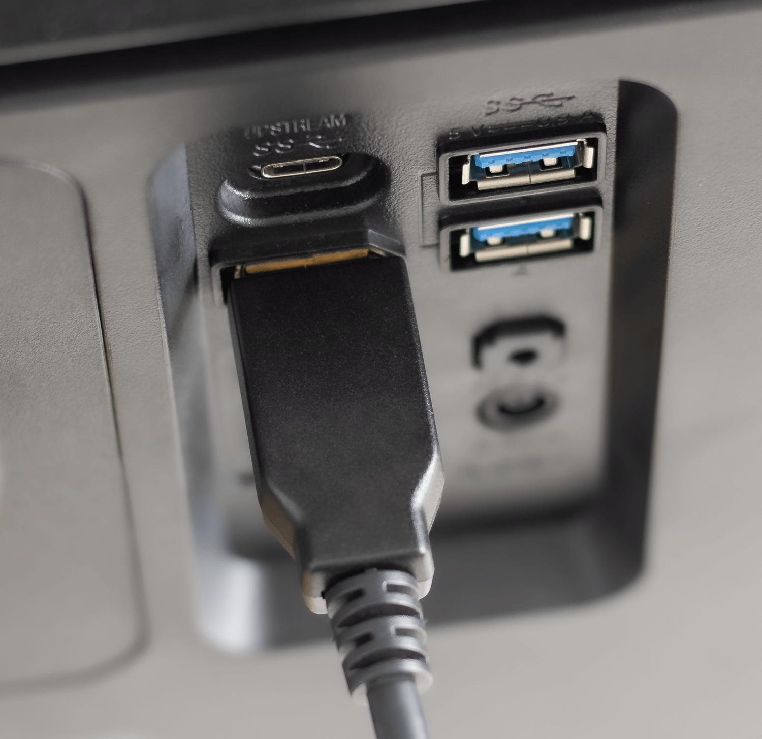 Zbliżenie czarnego kabla podłączonego do urządzenia. Dwa niebieskie porty USB widoczne powyżej.