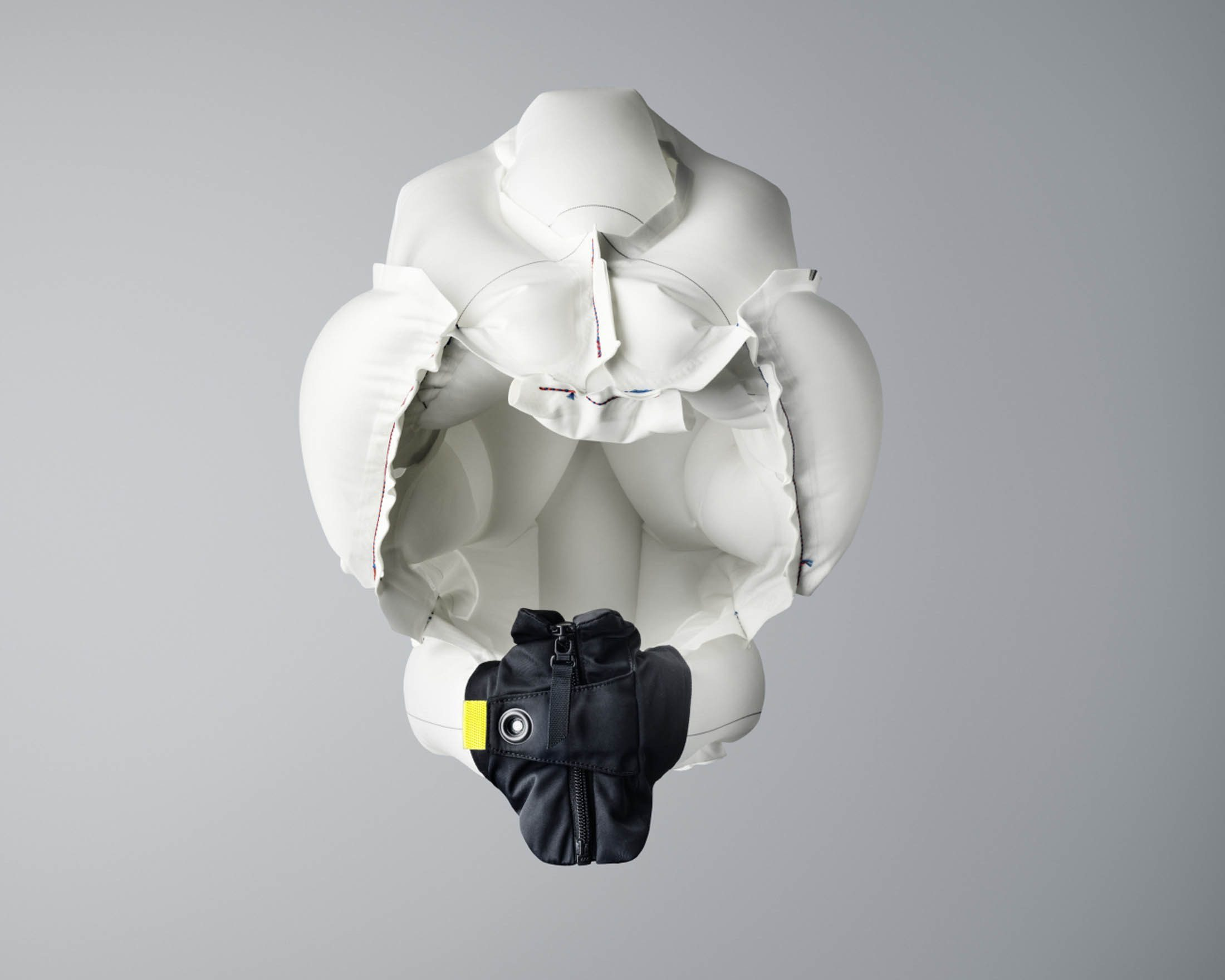 Aufgeblasene Airbag-Jacke offen, mit schwarzer Jacke darin, auf grauem Hintergrund.