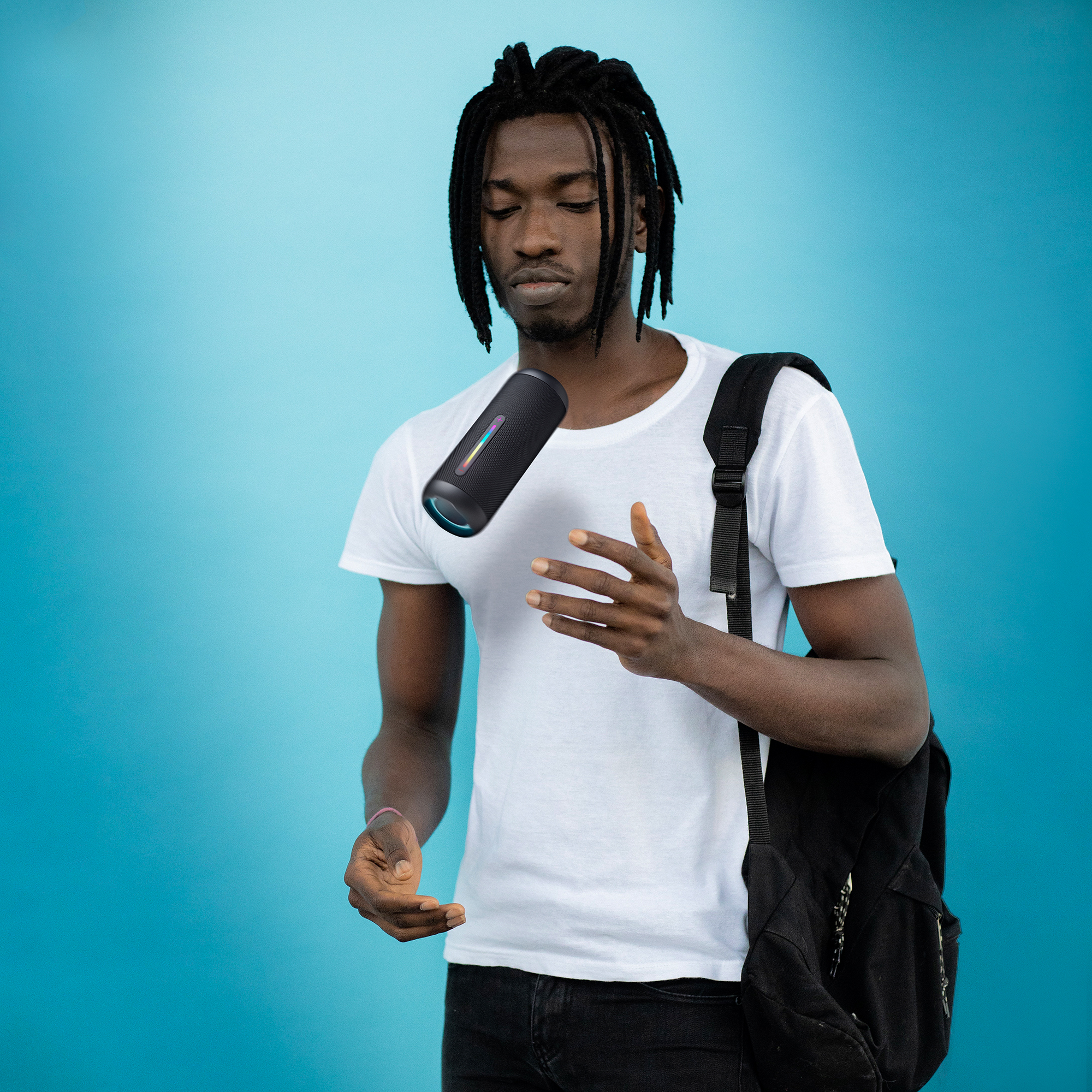 Mężczyzna lewituje czarny, cylindryczny głośnik na niebieskim tle.